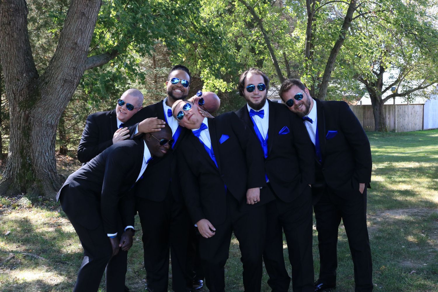 Groomsmen standing together being silly at wedding.
