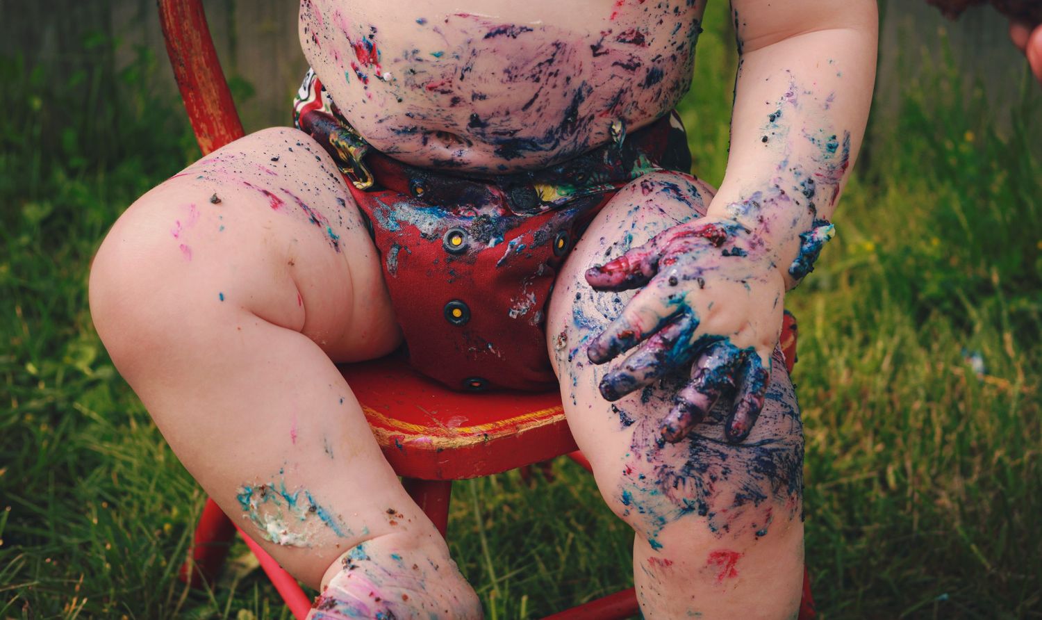 Close up of messy hands with cake and icing all over them from cake smash session.