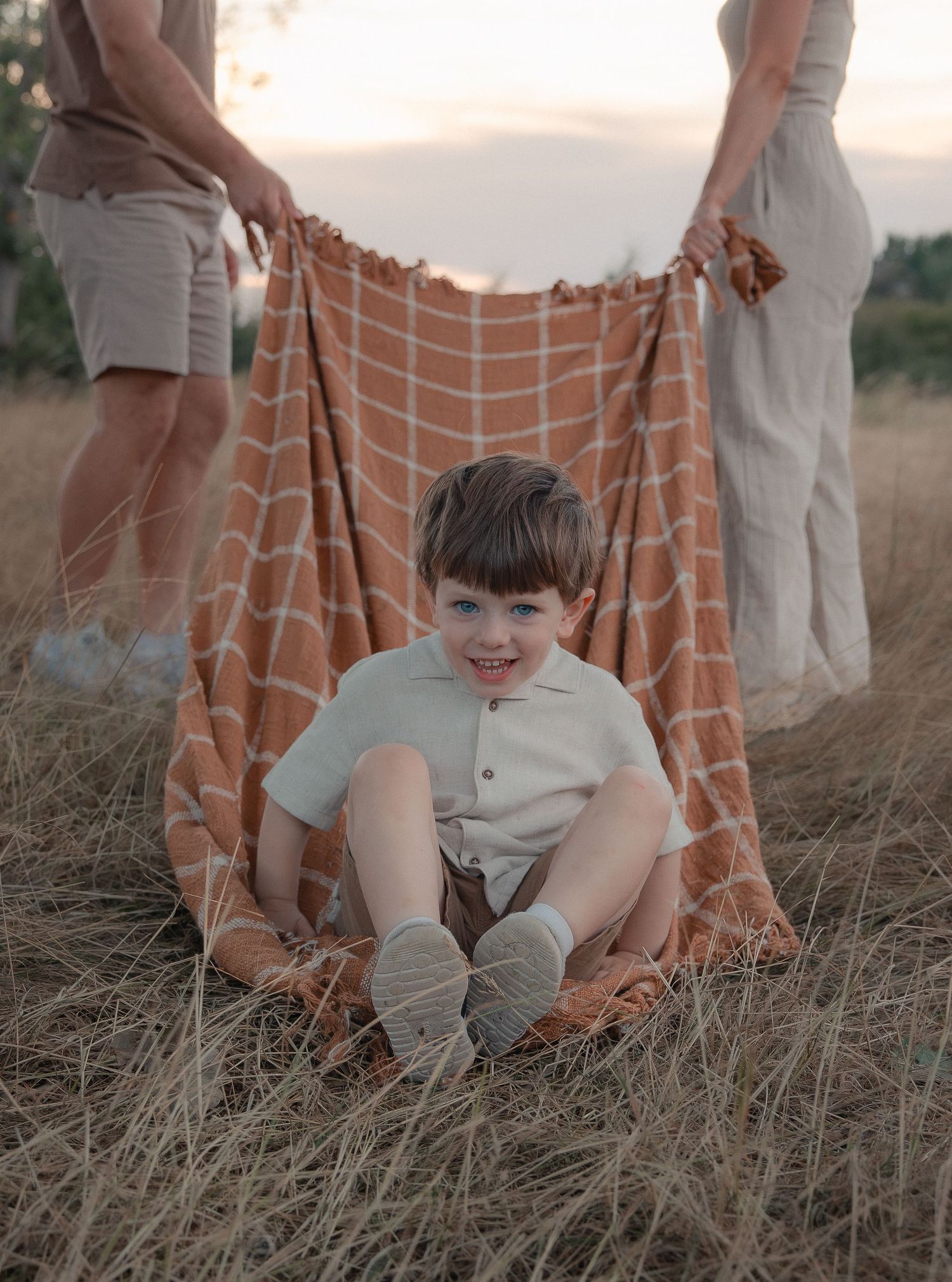 A family photographer captures a smiling boy as he sits on a blanket in Bath, Somerset.