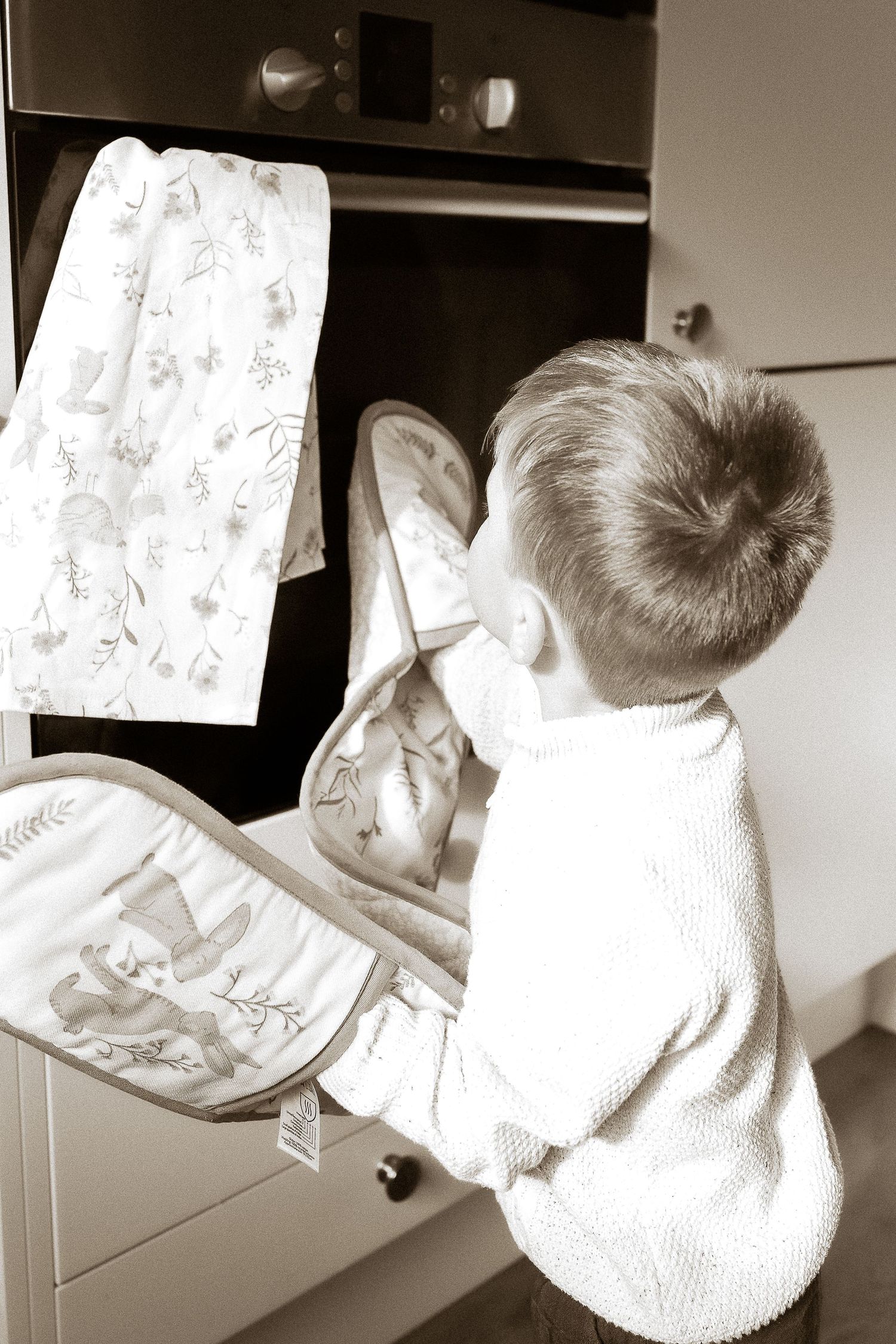 Storytelling Photoshoot of son admiring cakes in oven in Lower Slaughter, Cotswolds.