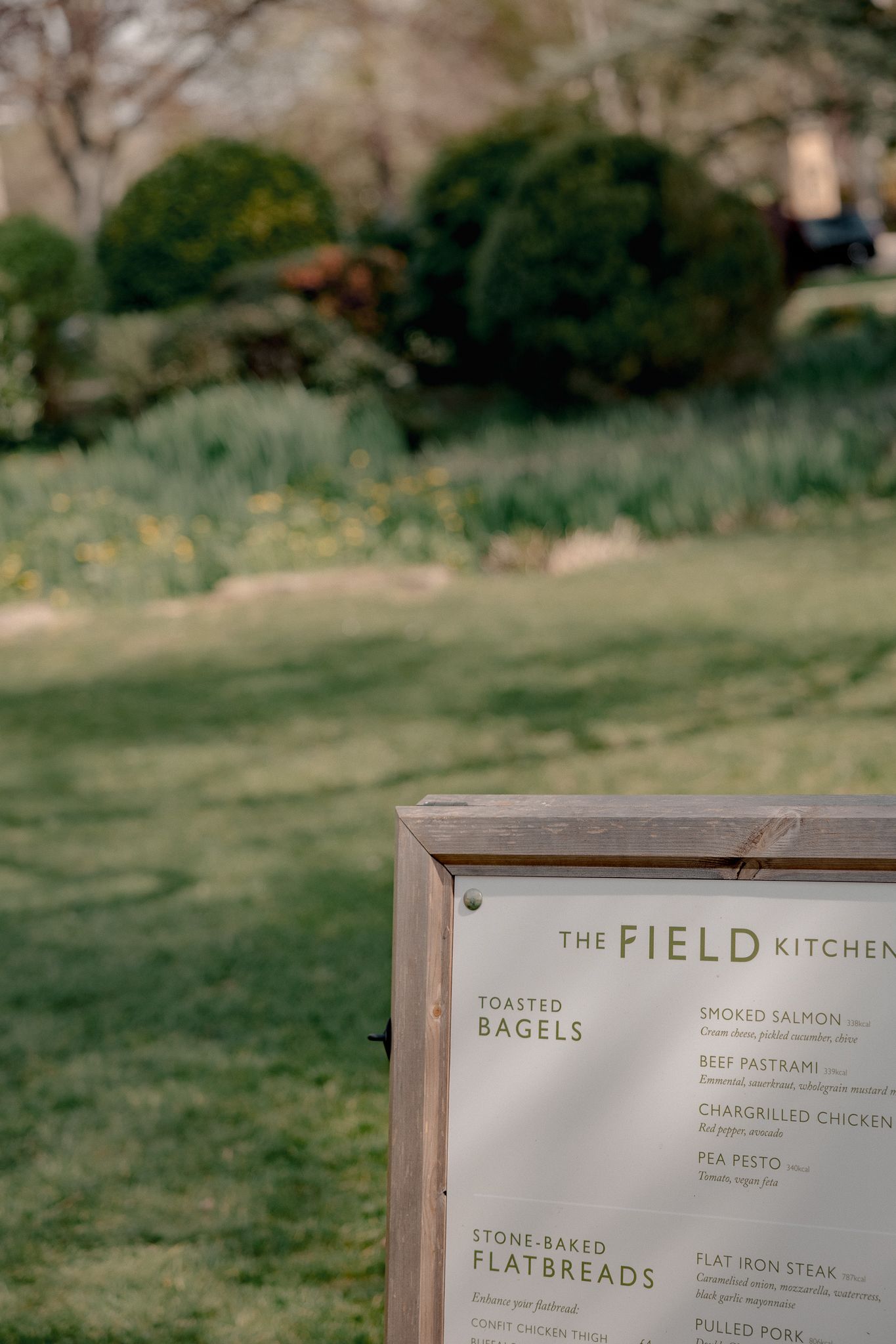 Wooden framed menu board for The Field Kitchen in a lush garden setting in Lower Slaughter, Cotswolds, UK.