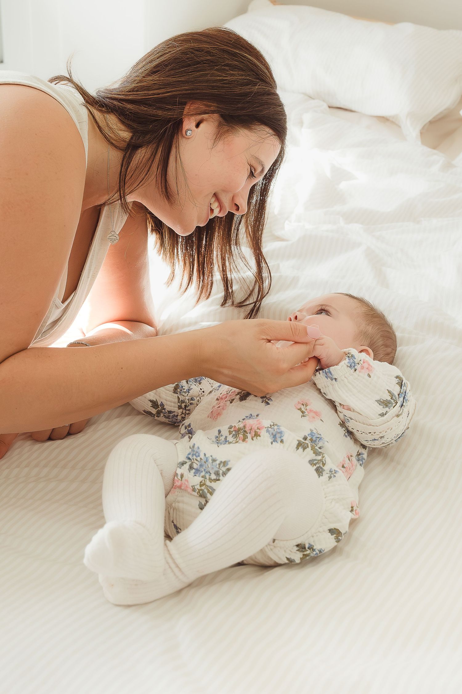 Newborn Photoshoot of loving mother smiling at her newborn baby lying in Bibury, Cotswolds.