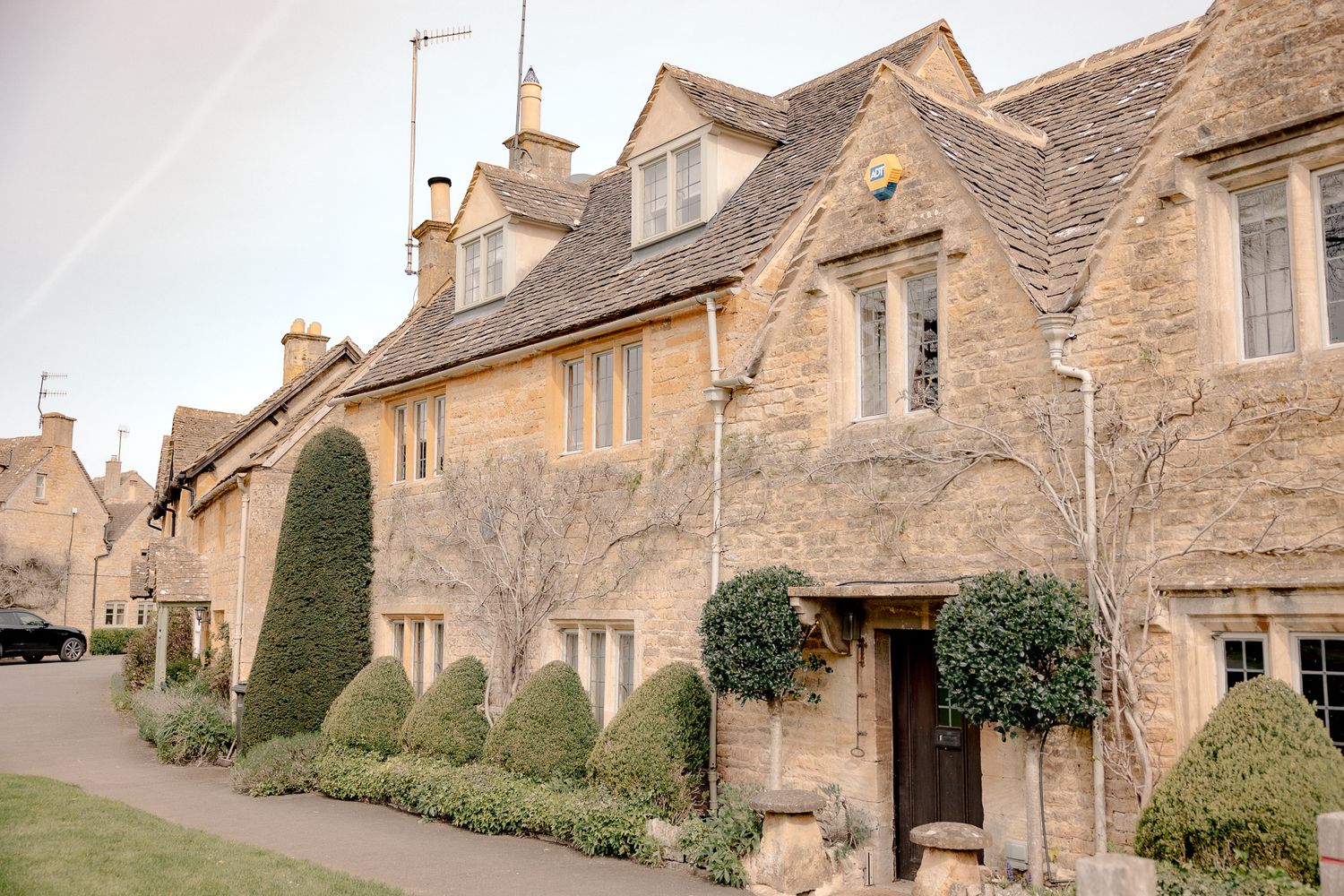 Charming Cotswold stone cottages with manicured topiary hedges lining a quiet village street in England in Lower Slaughter, Cotswolds, UK.