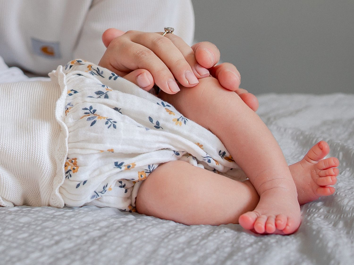 Close-up of a baby's legs and feet resting on a soft blanket while a parent gently holds them in Freshford.