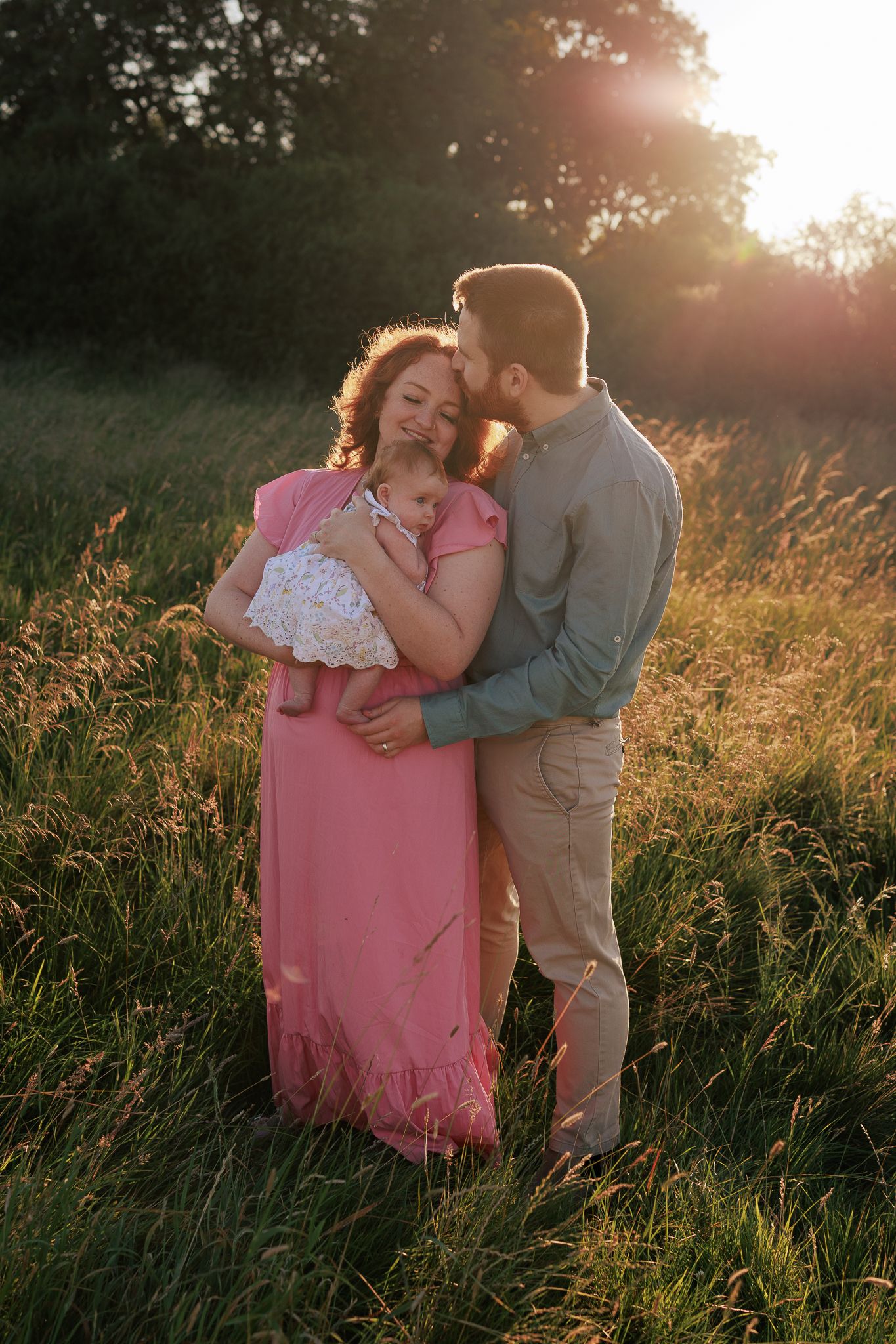 A couple stands in a sunlit field at golden hour in Marlborough.