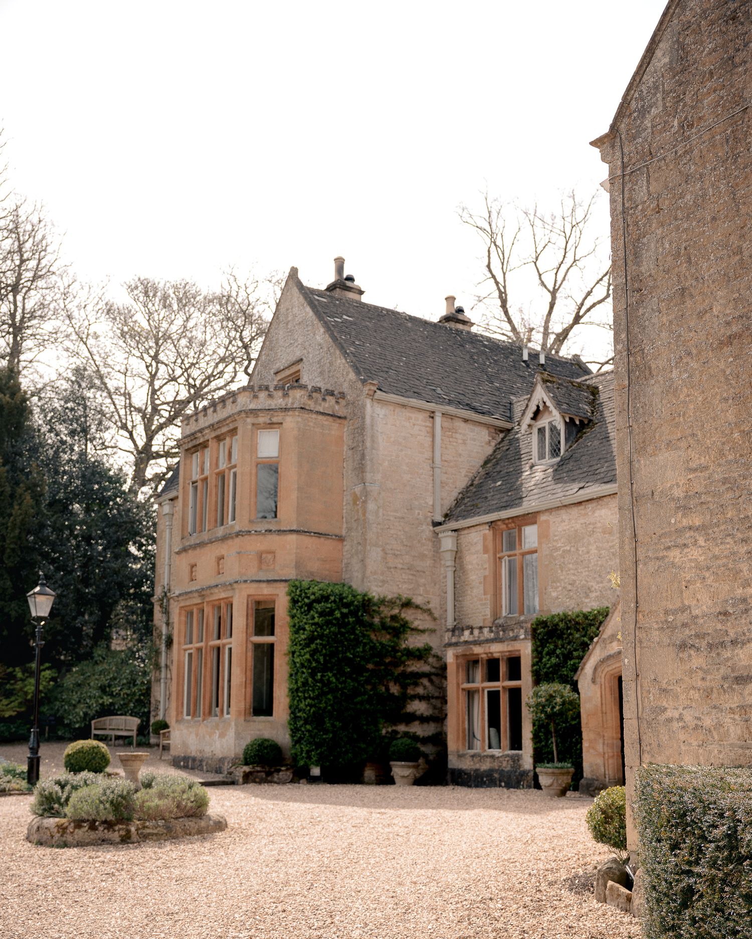 Lords of the Manor Hotel with bay windows, ivy-covered walls, and a gravel courtyard surrounded by manicured gardens.