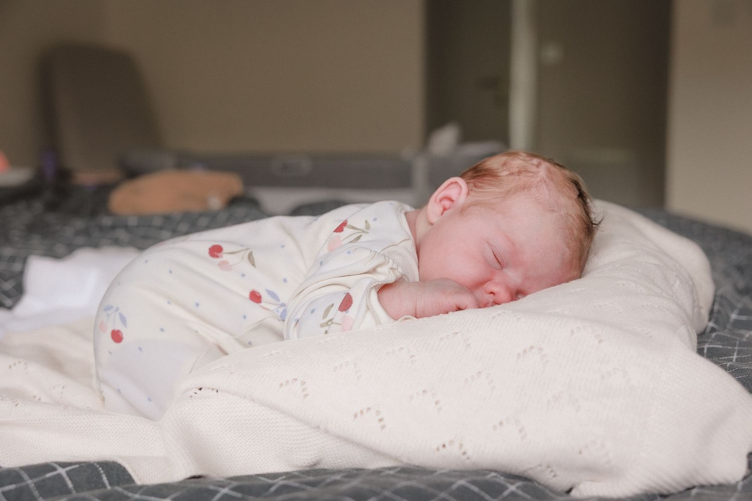 Newborn photoshoot of baby sleeping peacefully swaddled in a white blanket on a soft white pillow Great Tew, Cotswolds.