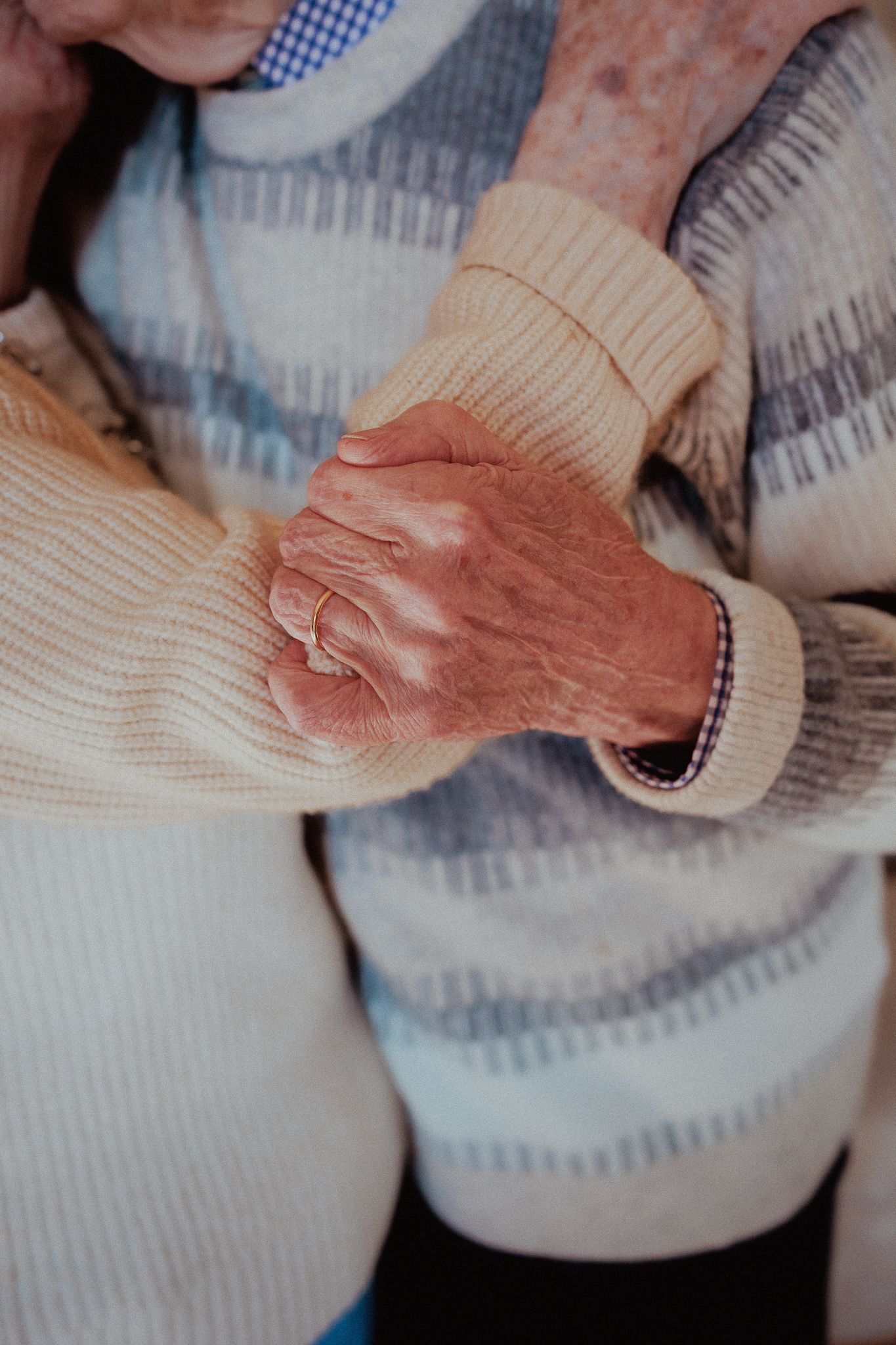 Elderly couple holding hands tenderly, showcasing a timeless bond and enduring love in Wantage.