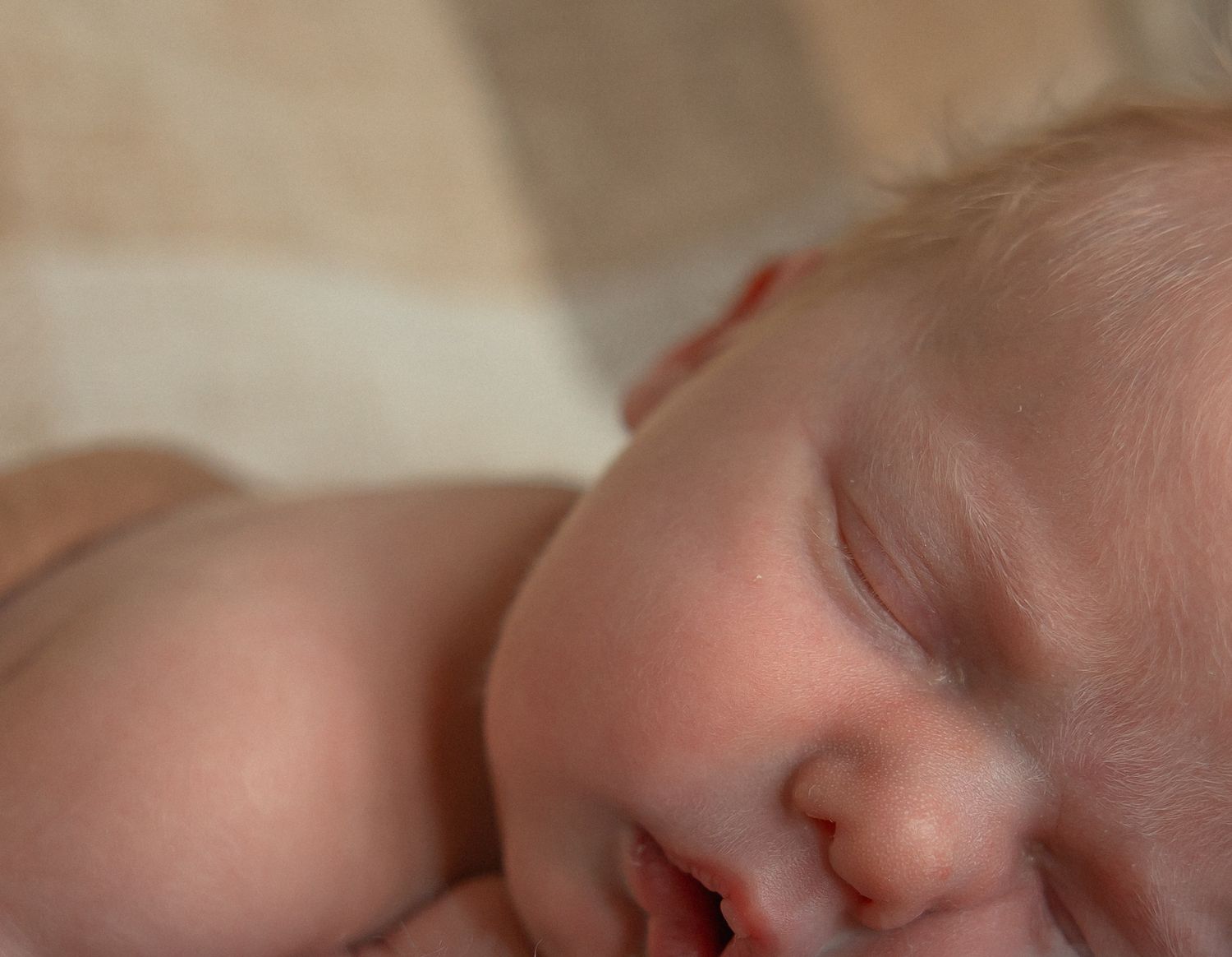 Close-up photo of a sleeping baby's face with rosy cheeks and peaceful expression.