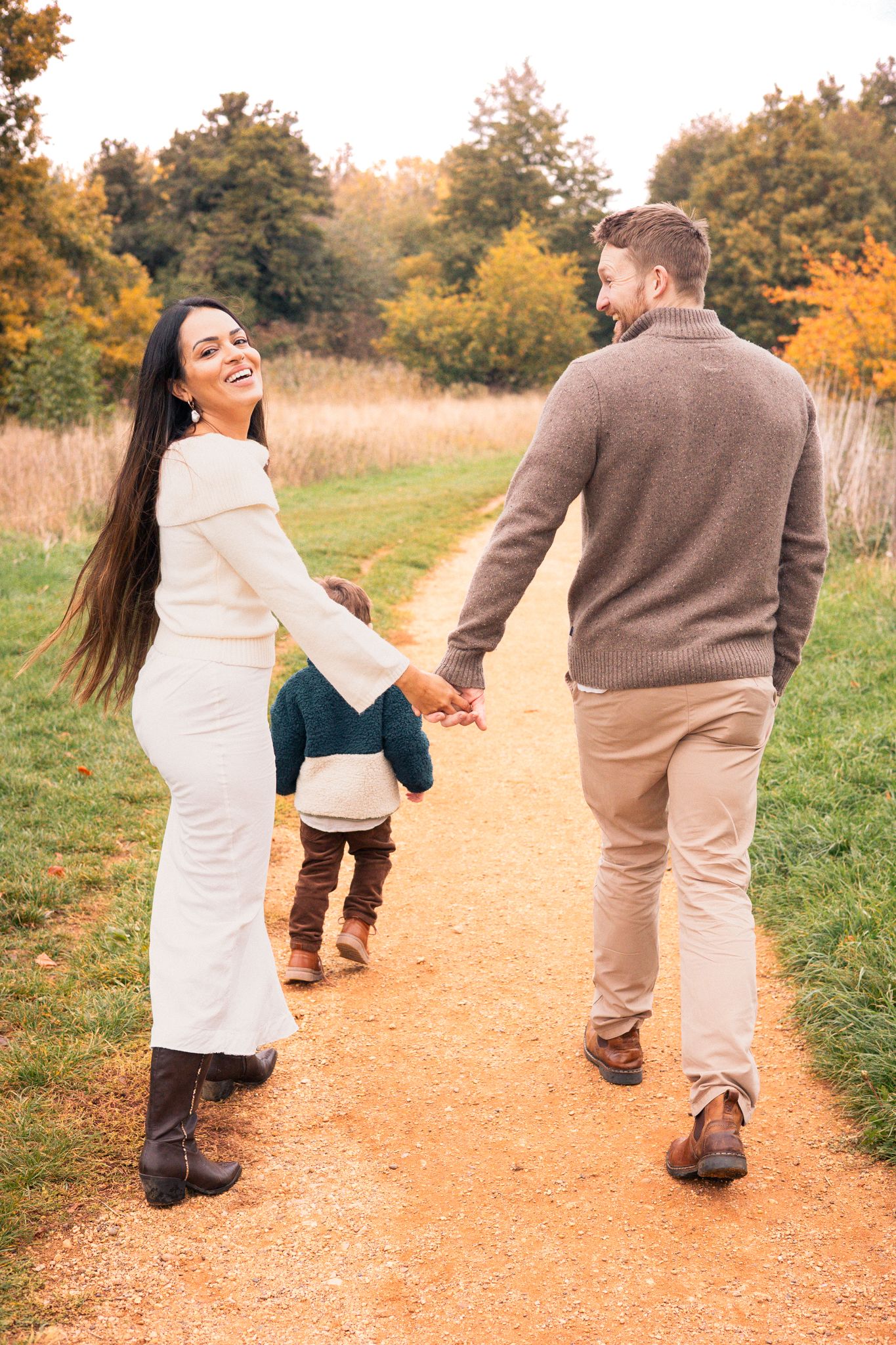 Family walking together on autumn path holding hands. Tetbury, Cotswolds.