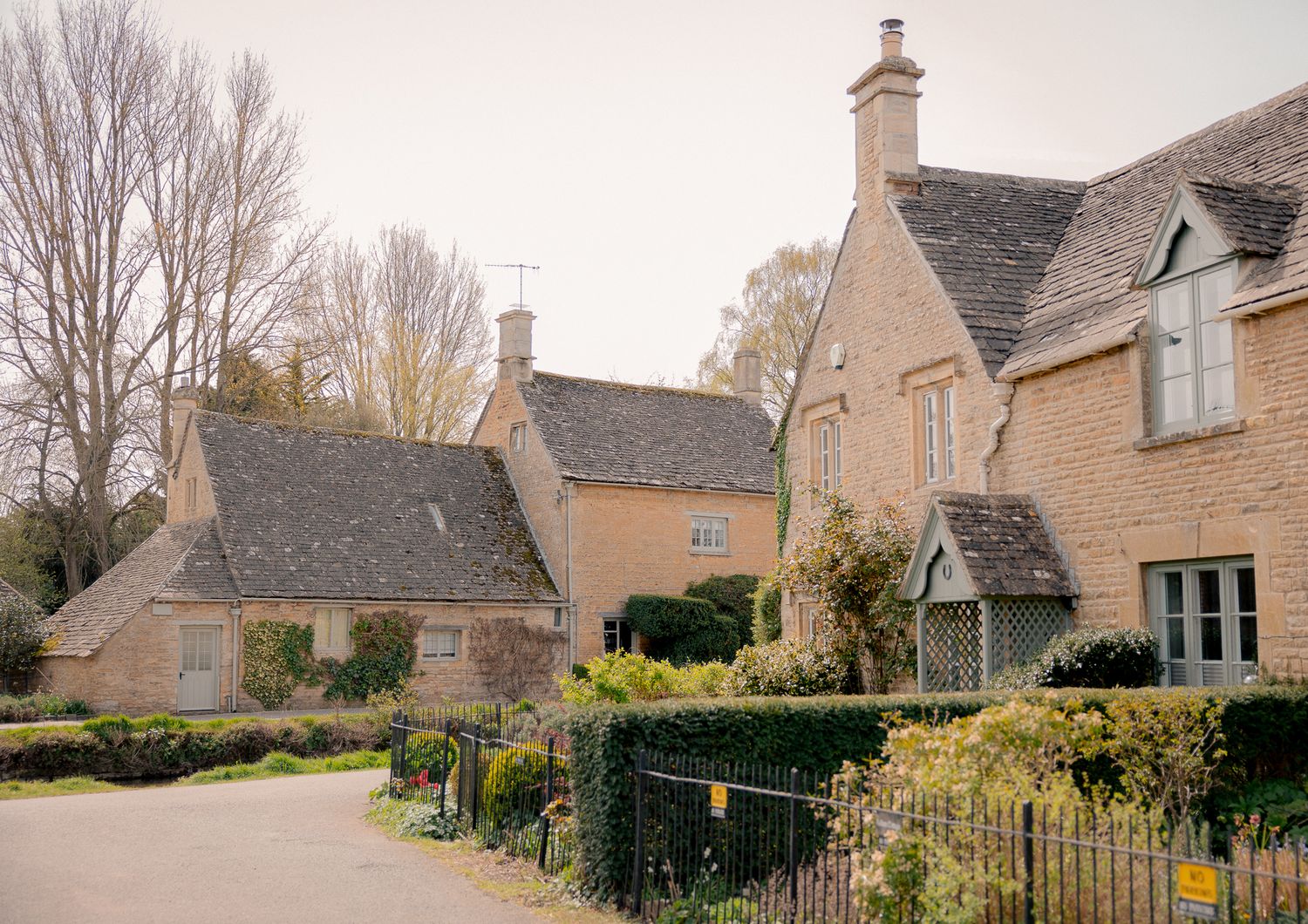 Charming Cotswold stone cottages line a quiet village lane surrounded by mature trees and lush hedgerows.  in Lower Slaughter, Cotswolds, UK