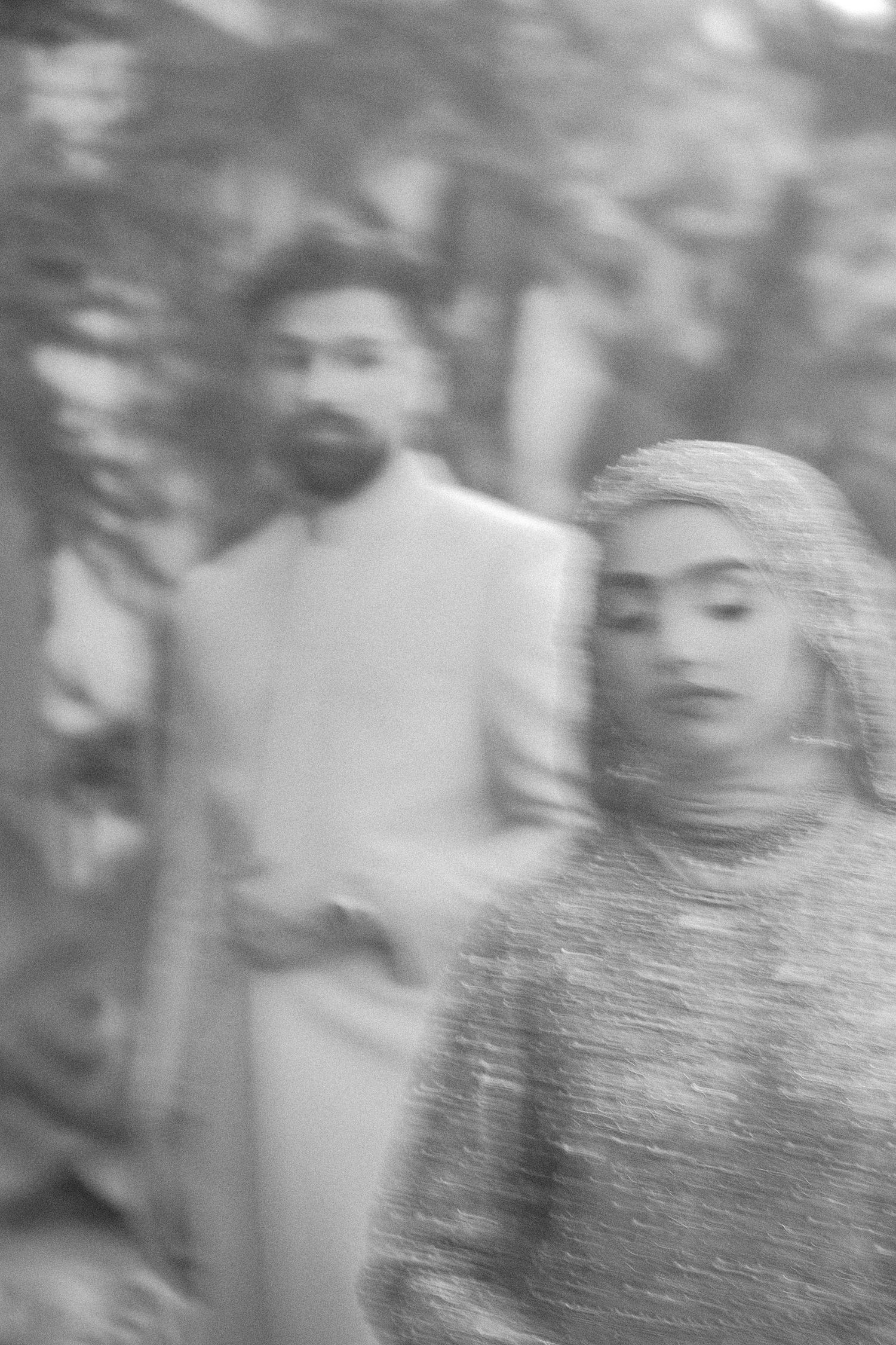 Black and white blurry photo of South Asian wedding couple, groom in sherwani and bride in embroidered dupatta.