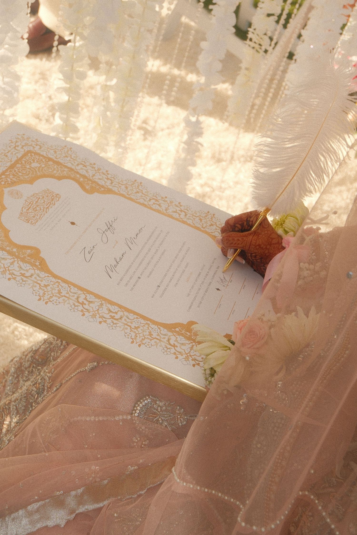 Bride signing Islamic nikah marriage contract with gold pen, henna hands, white feather quill, ornate gold border certificate.