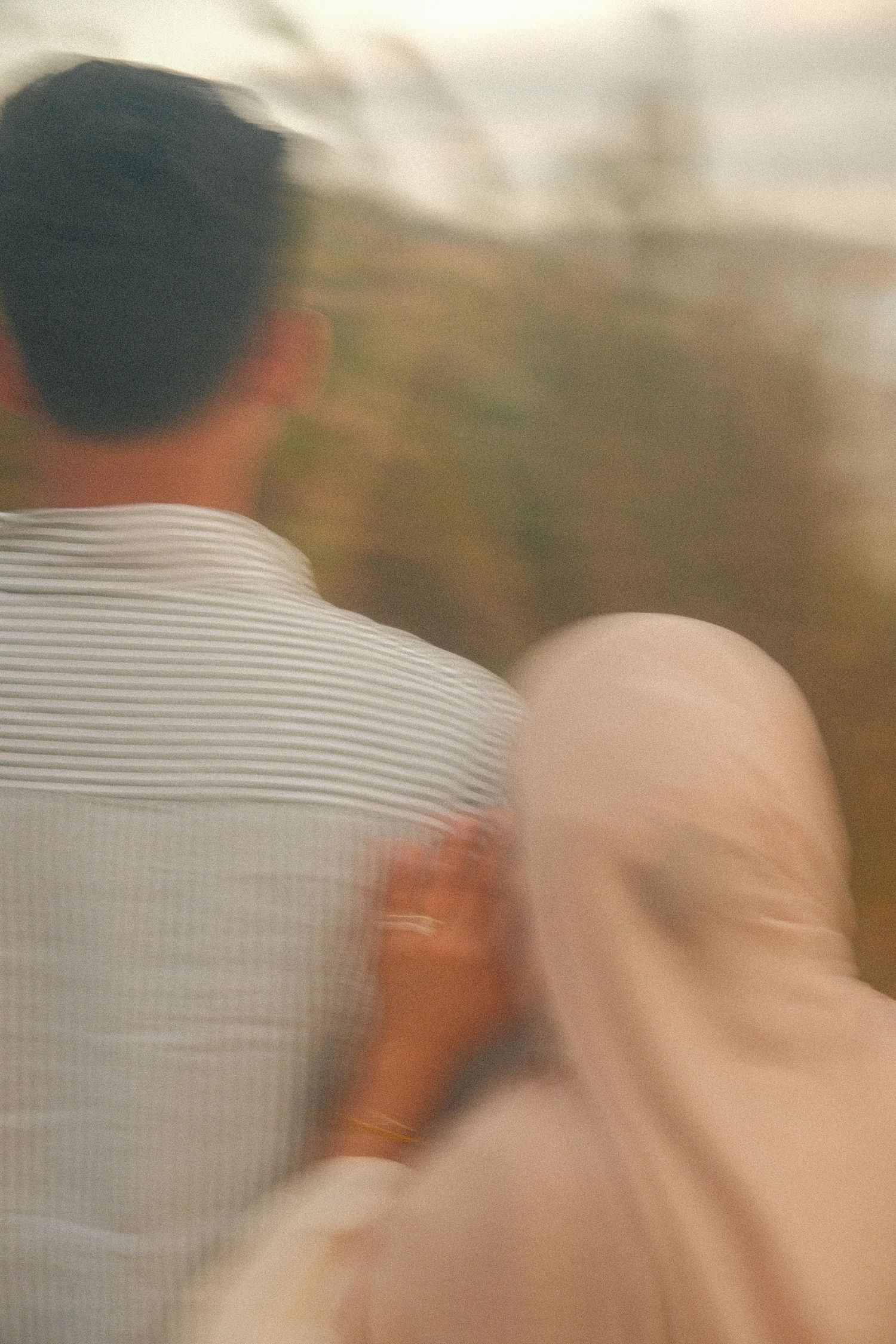 Blurred motion shot of a couple sitting together outdoors, woman in hijab resting hand on man's back.
