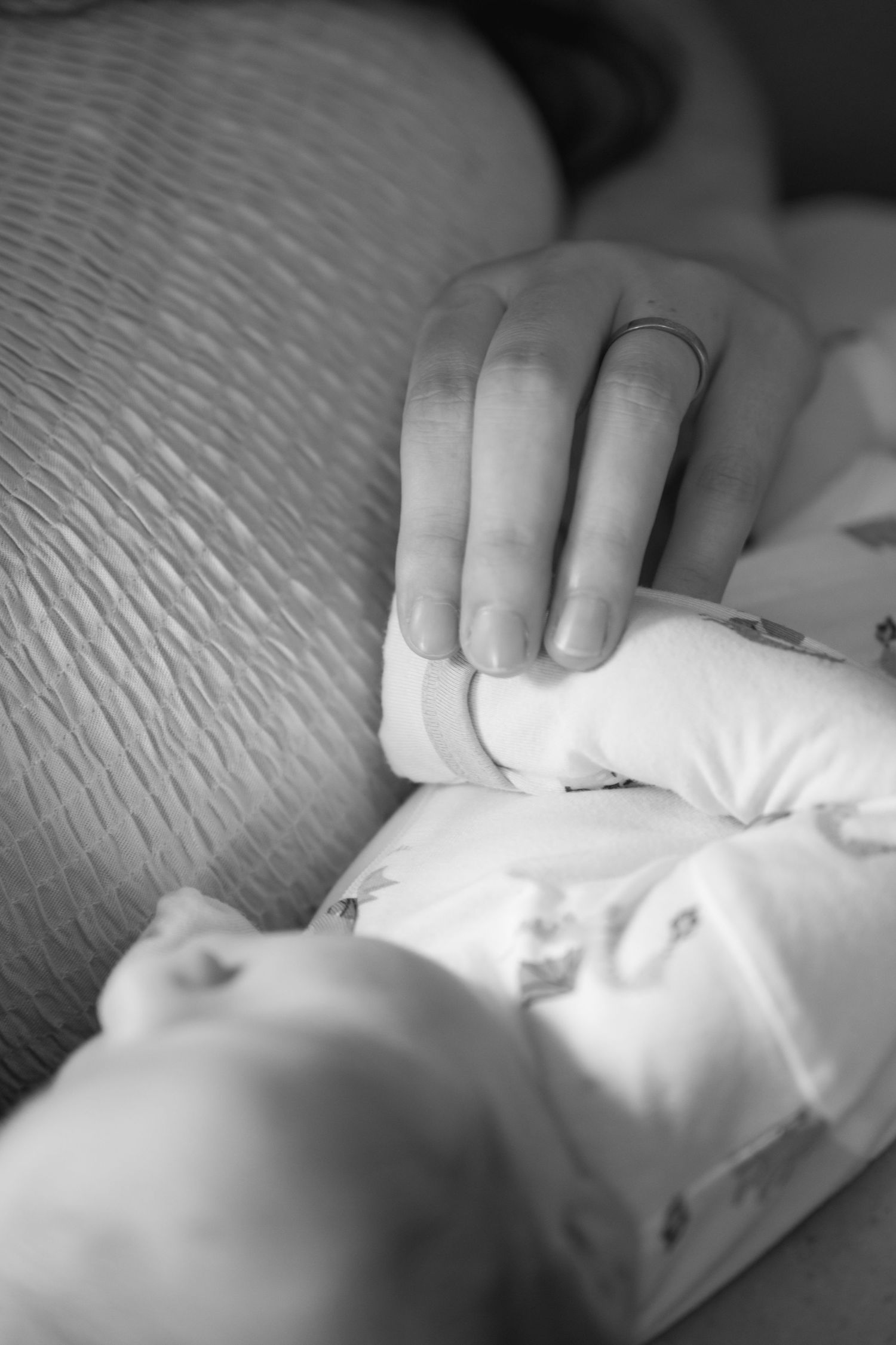 lifestyle Black and white close-up of a parent gently holding a sleeping newborn baby