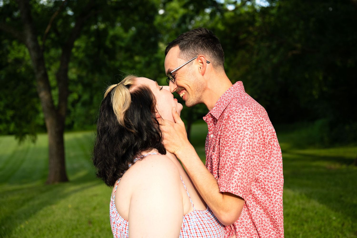 portrait of a Romantic couple sharing a close moment nearly kissing outdoors in a sunlit green park.