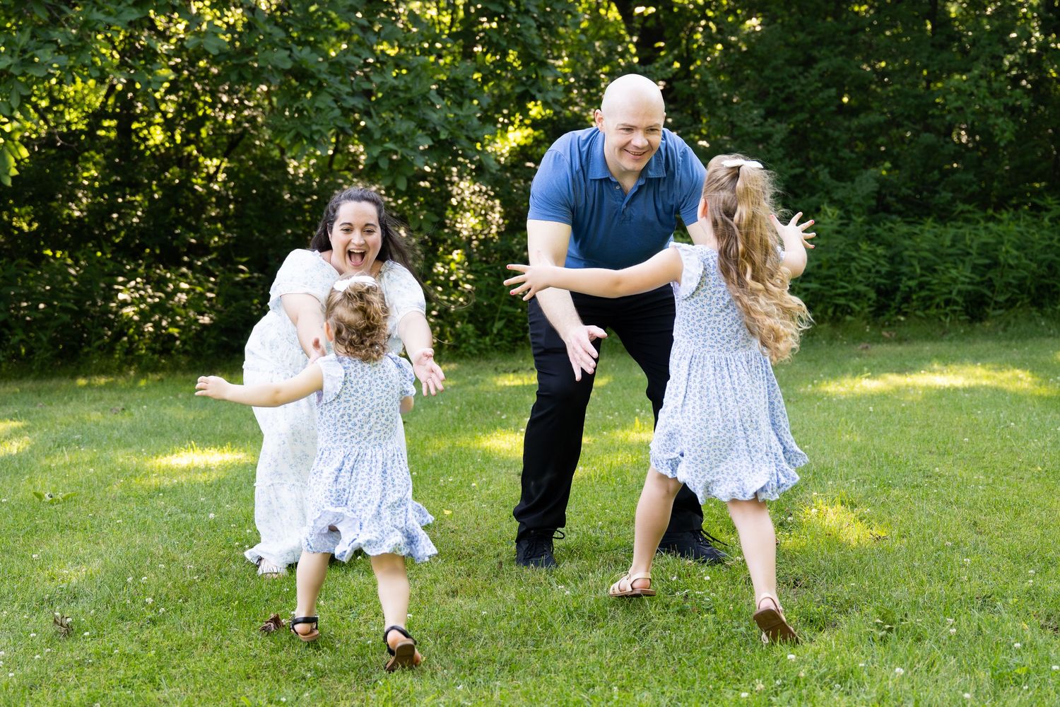 lifestyle portrait of A joyful family playing  outdoors on green grass, with two girls in white dresses