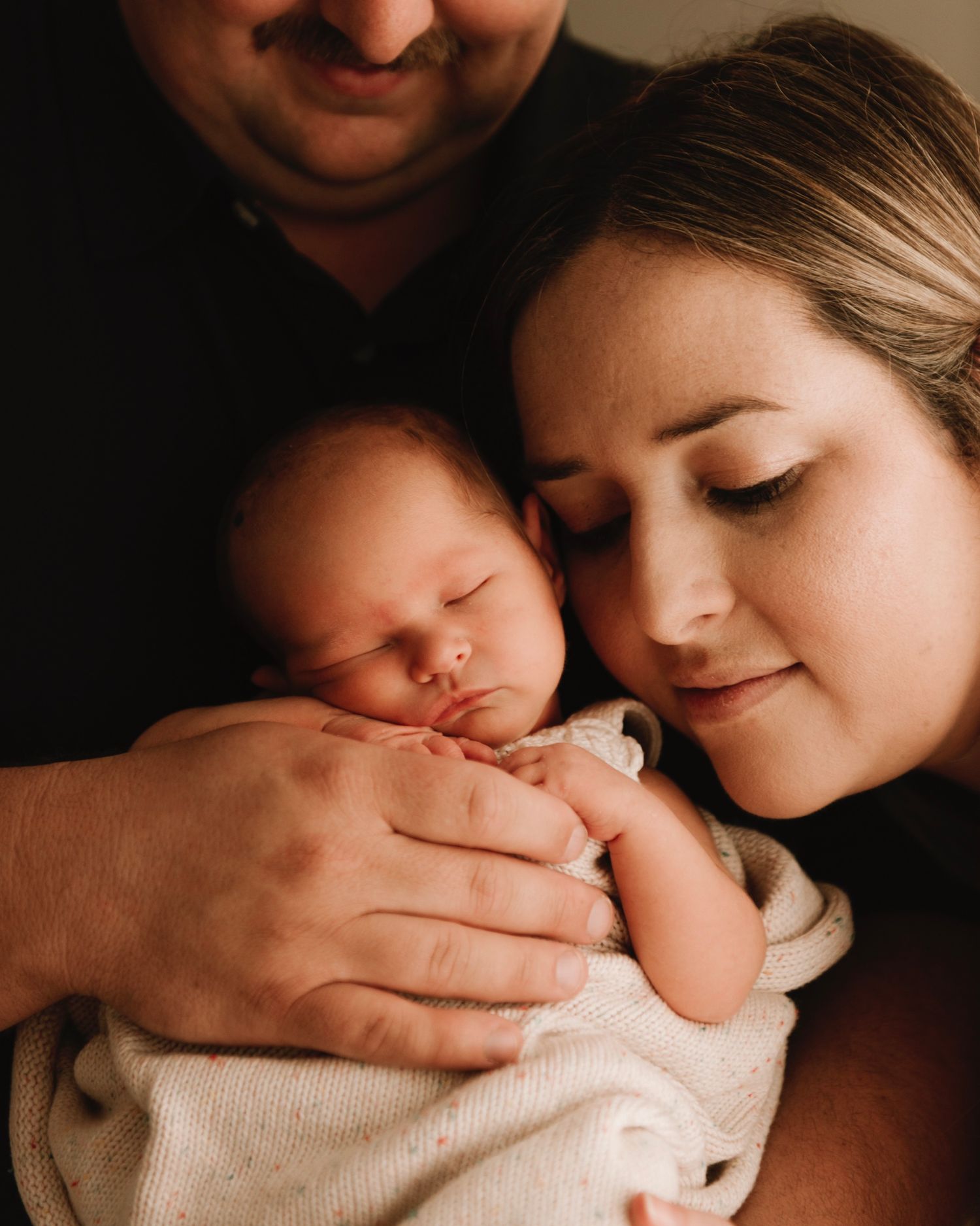 in-home newborn photography Sydney of parents cuddling their newborn rainbow baby in soft light