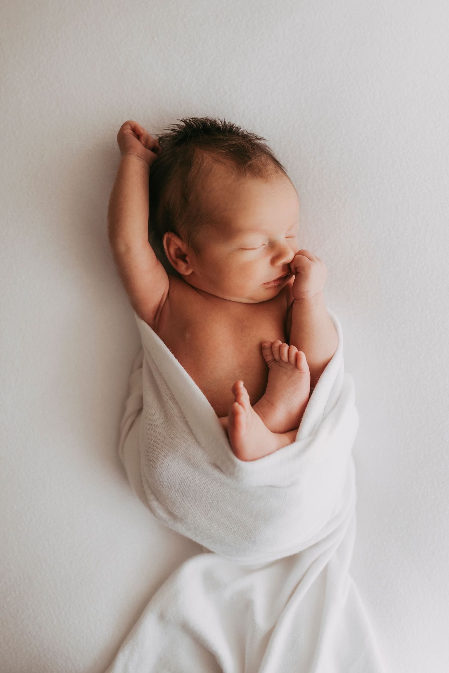 in-home newborn photography Sydney of newborn baby wrapped and sleeping peacefully on bed