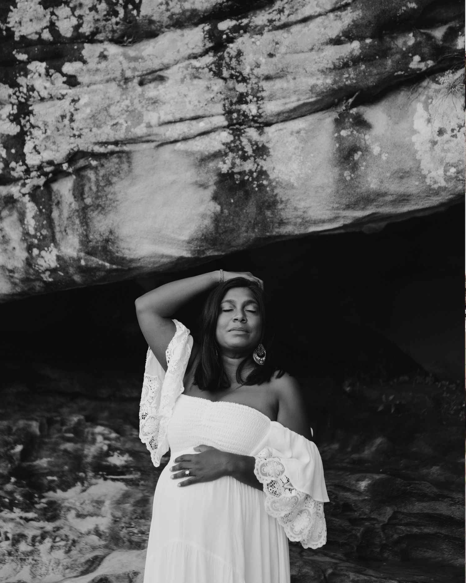 Mosman maternity photography of mother-to-be standing beneath rock formation in black and white.  ivf success story Rainbow baby