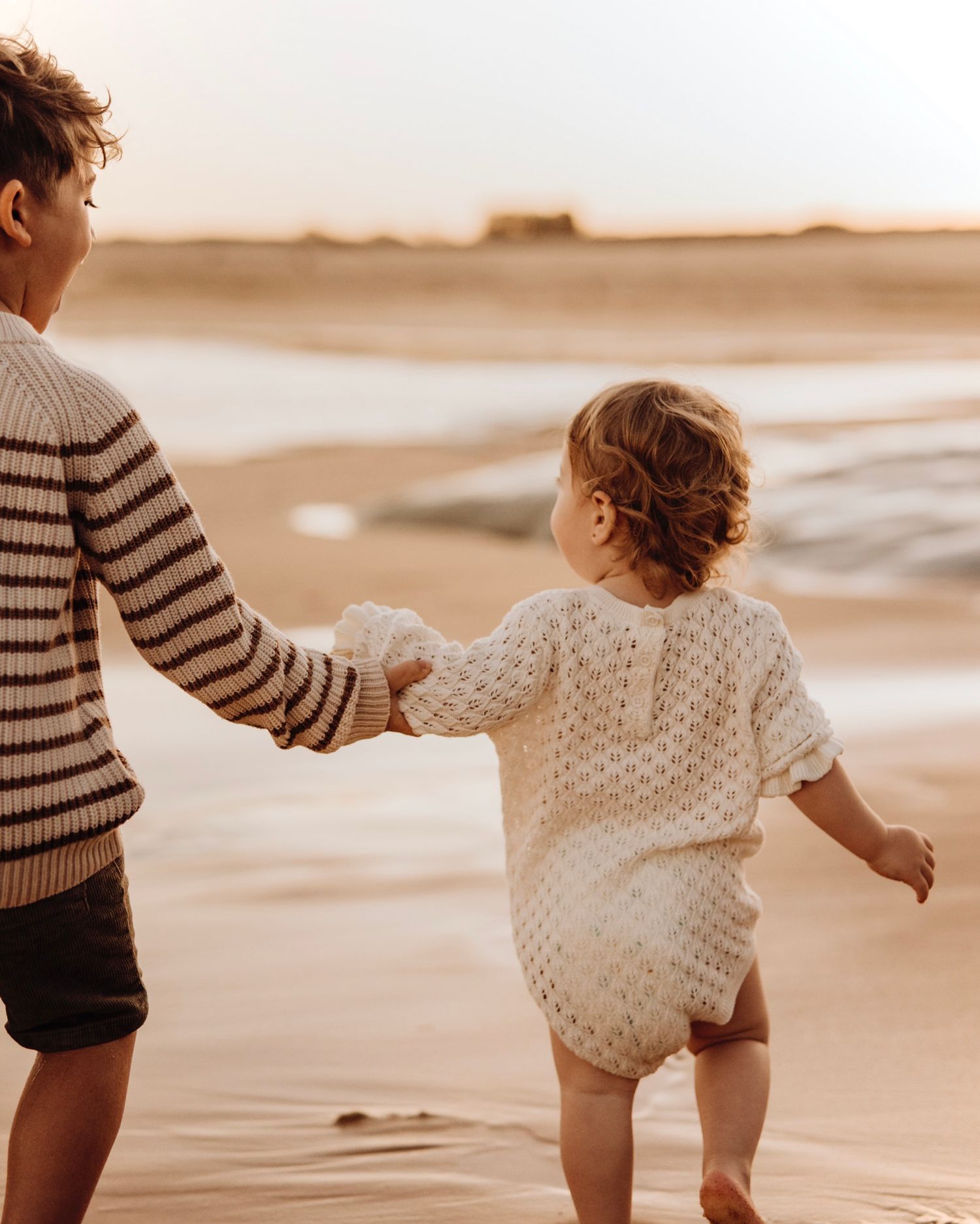 Northern Beaches family photography of siblings holding hands walking along the beach