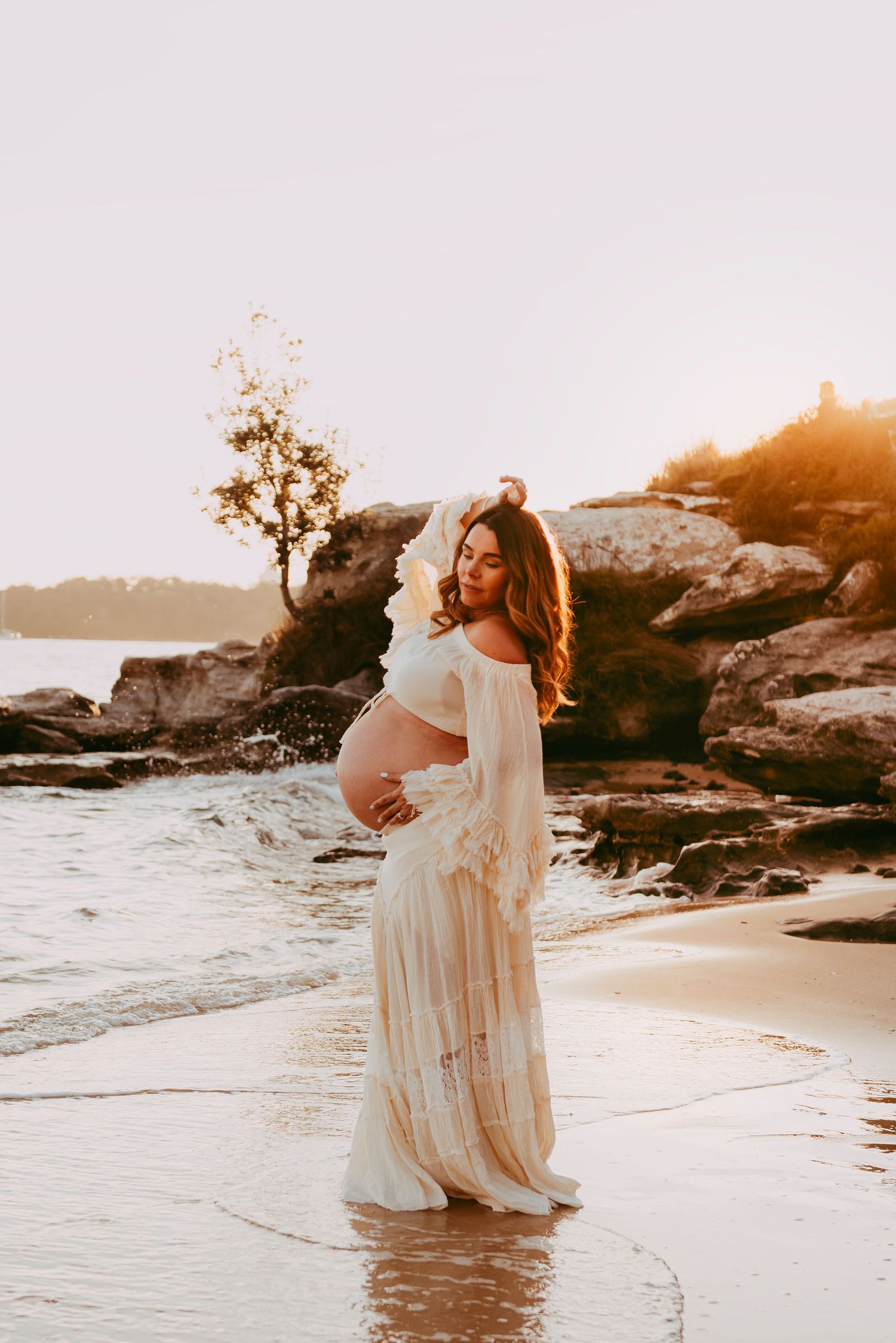 maternity photography Vaucluse Sydney of pregnant mother standing in water at sunset on Sydney Harbour beach, rainbow baby