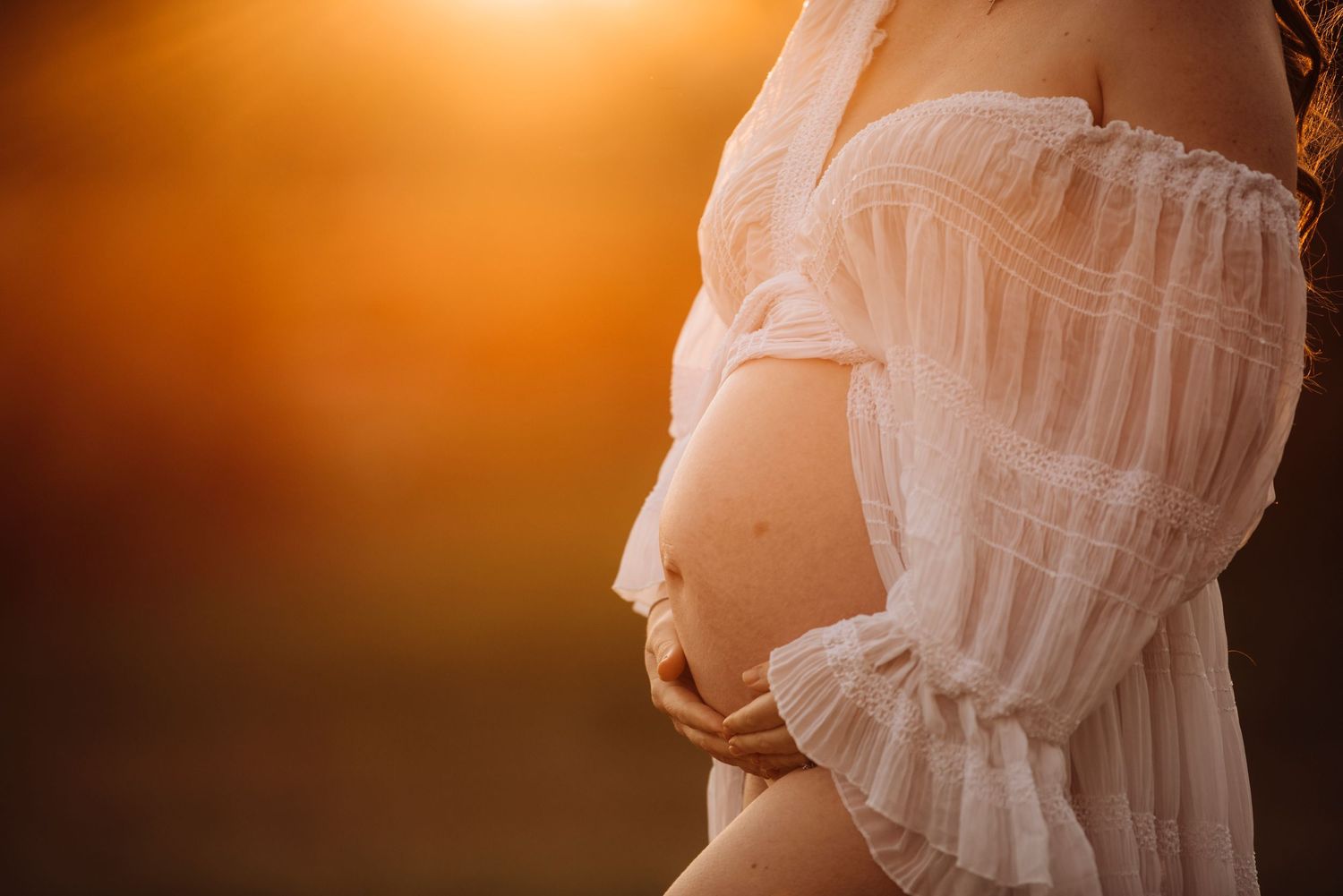 pregnant woman holding her belly at sunset maternity photography Sydney natural light IVF rainbow family