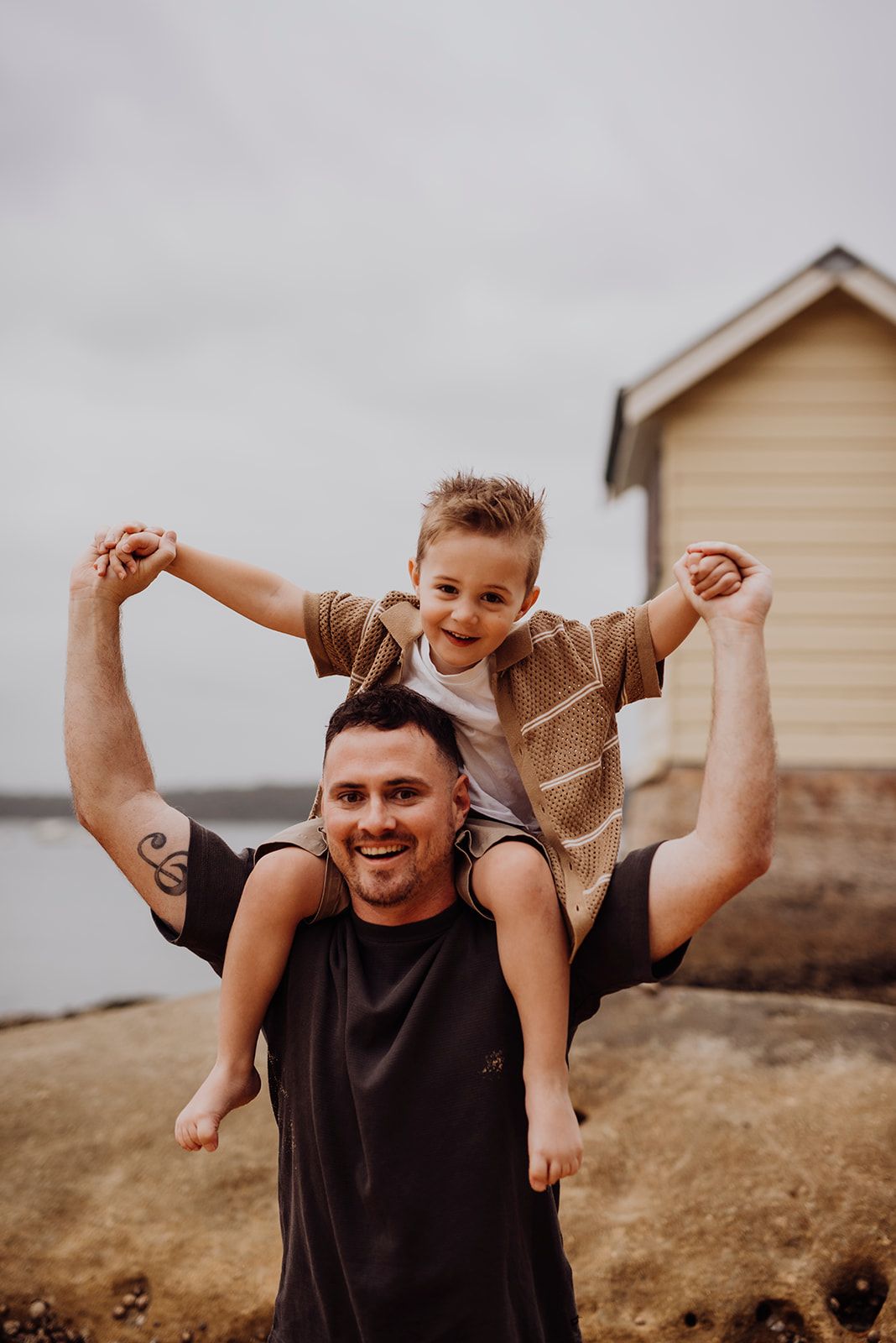 Watsons Bay family photography of father lifting child on shoulders near the beach huts