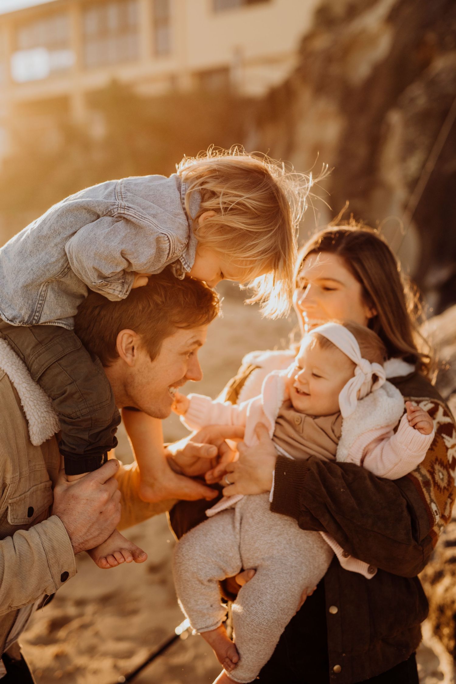 family photography Northern Beaches Sydney of parents walking with children along beach at sunset, relaxed candid moment