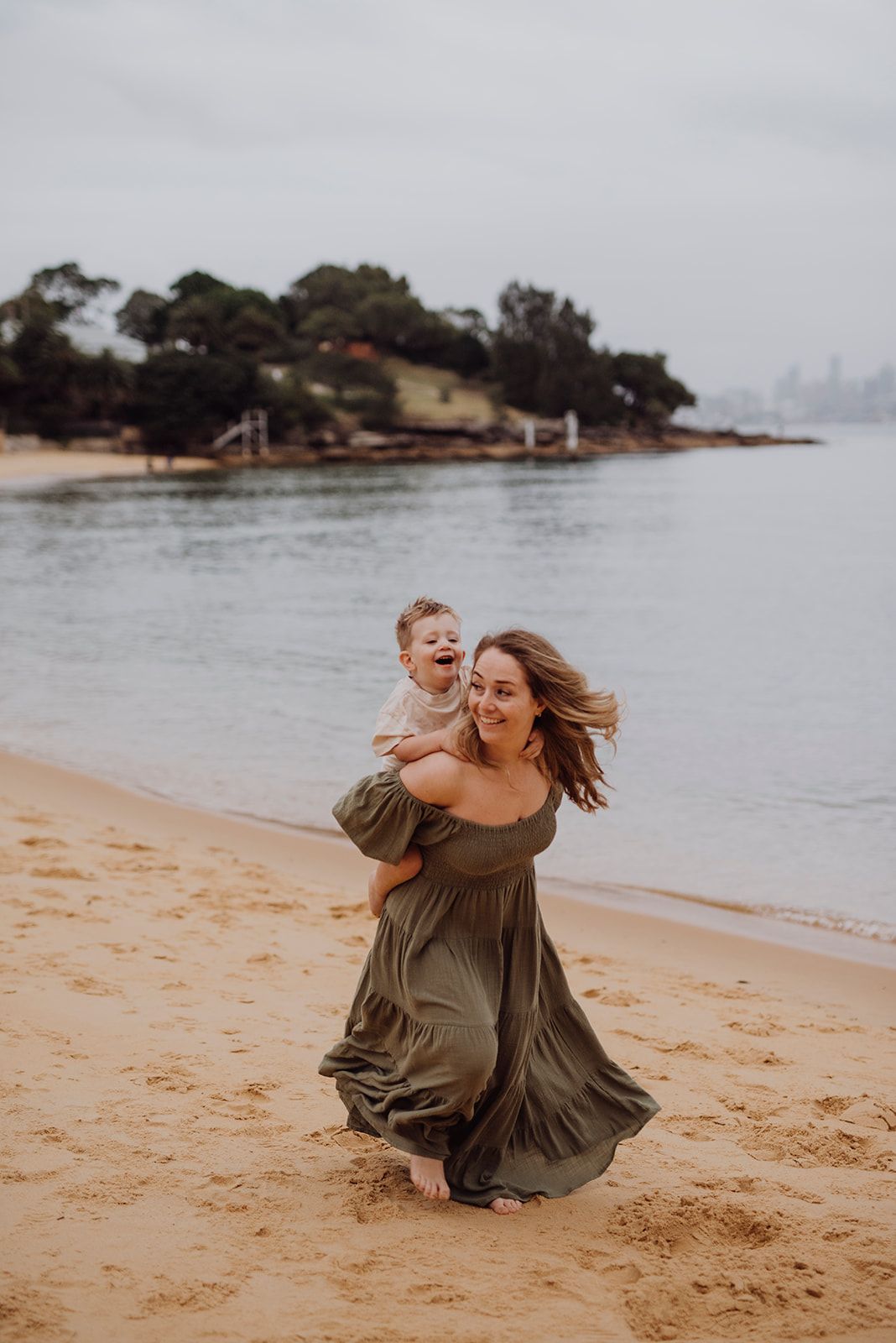 Watsons Bay family photography of mother spinning with child along the shoreline after IVF