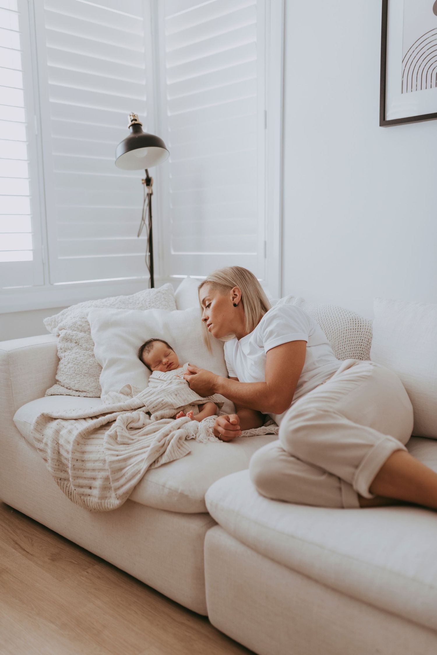 in-home newborn photography Sydney of mother lying on sofa with newborn baby in soft natural light