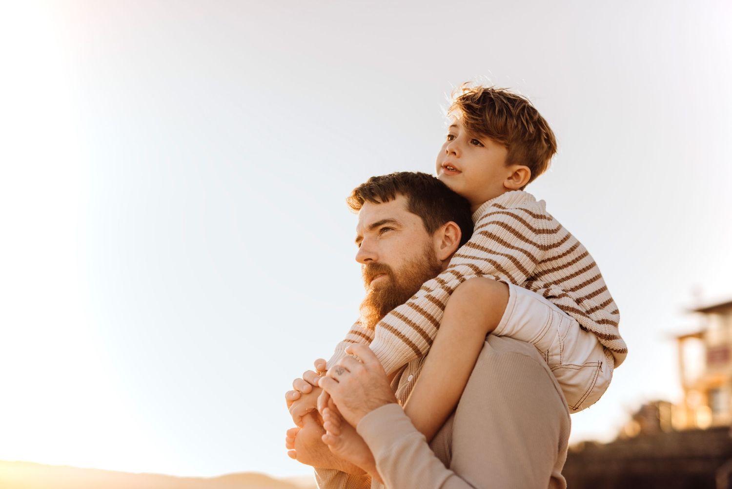 Northern Beaches family photography of father holding son on his shoulders in warm evening light