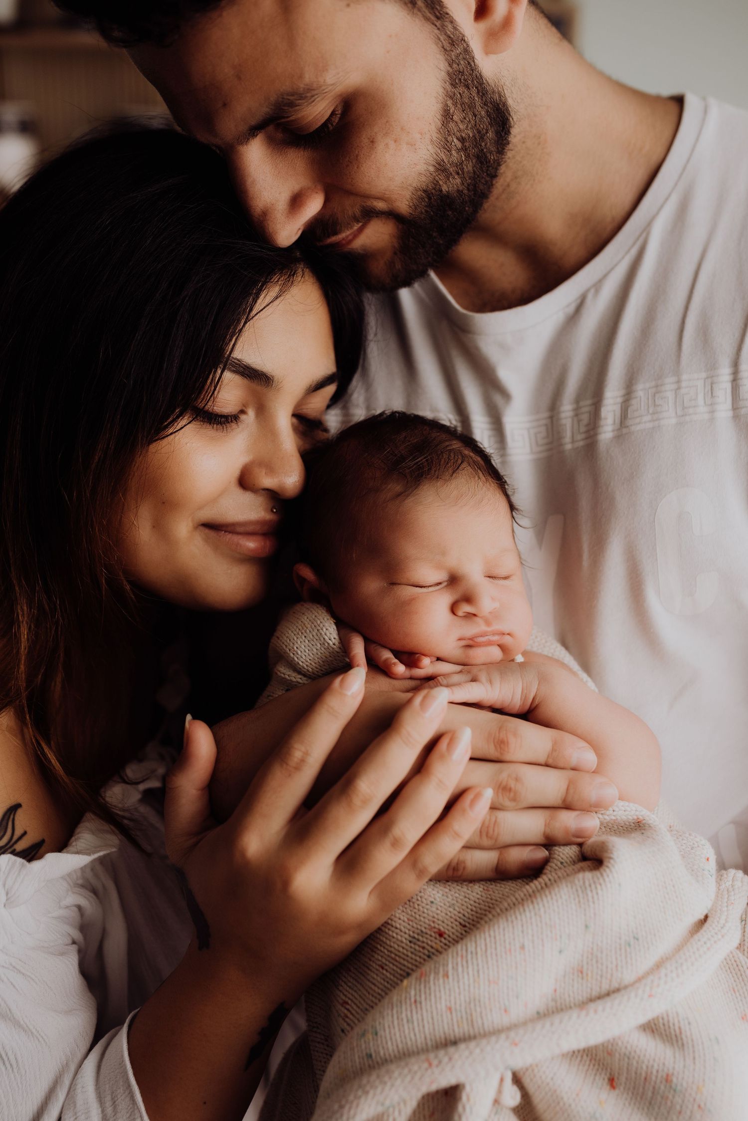 Sydney newborn photography of parents cuddling baby in warm connected moment