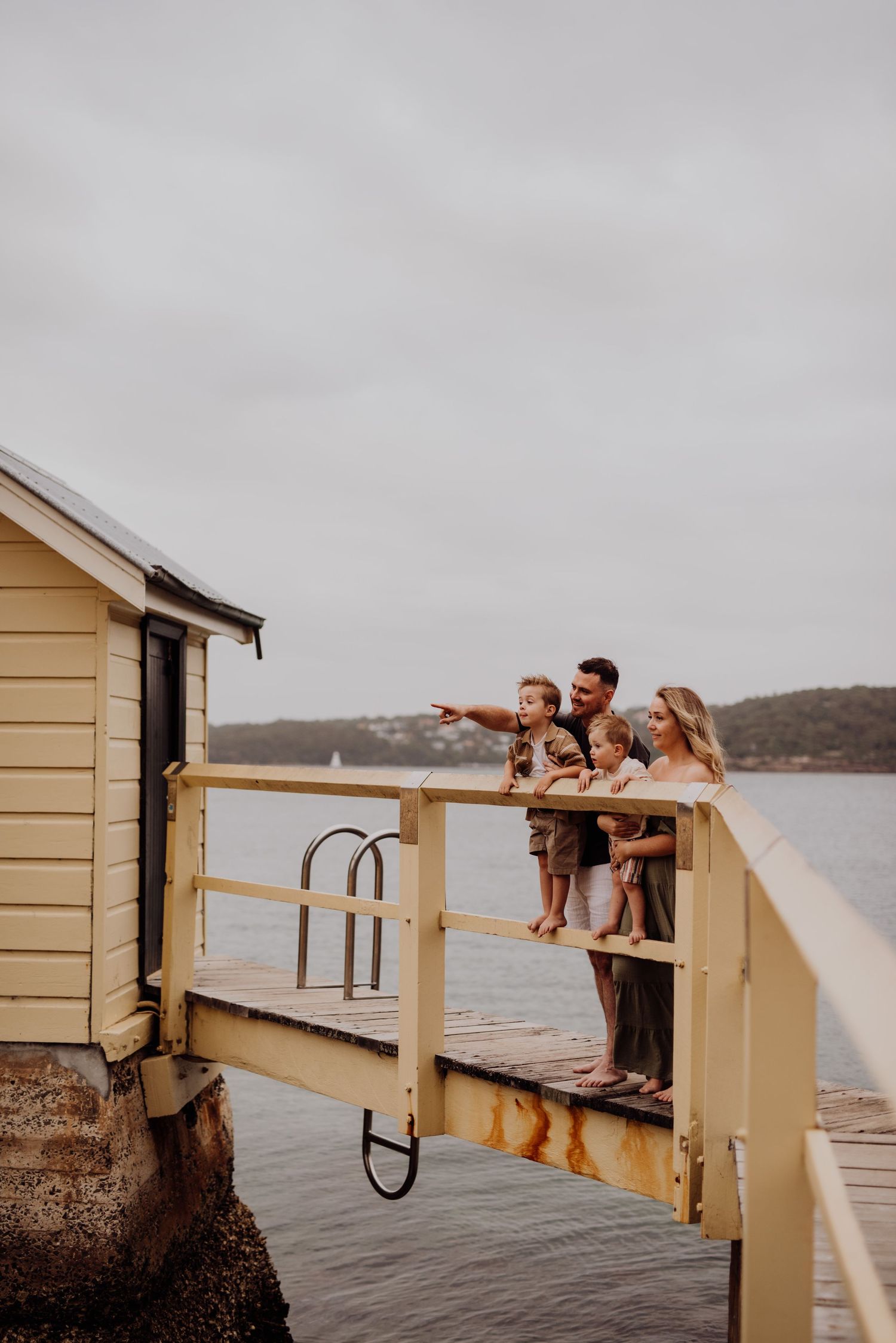 Watsons Bay family photography of parents with young children standing on wharf overlooking the water