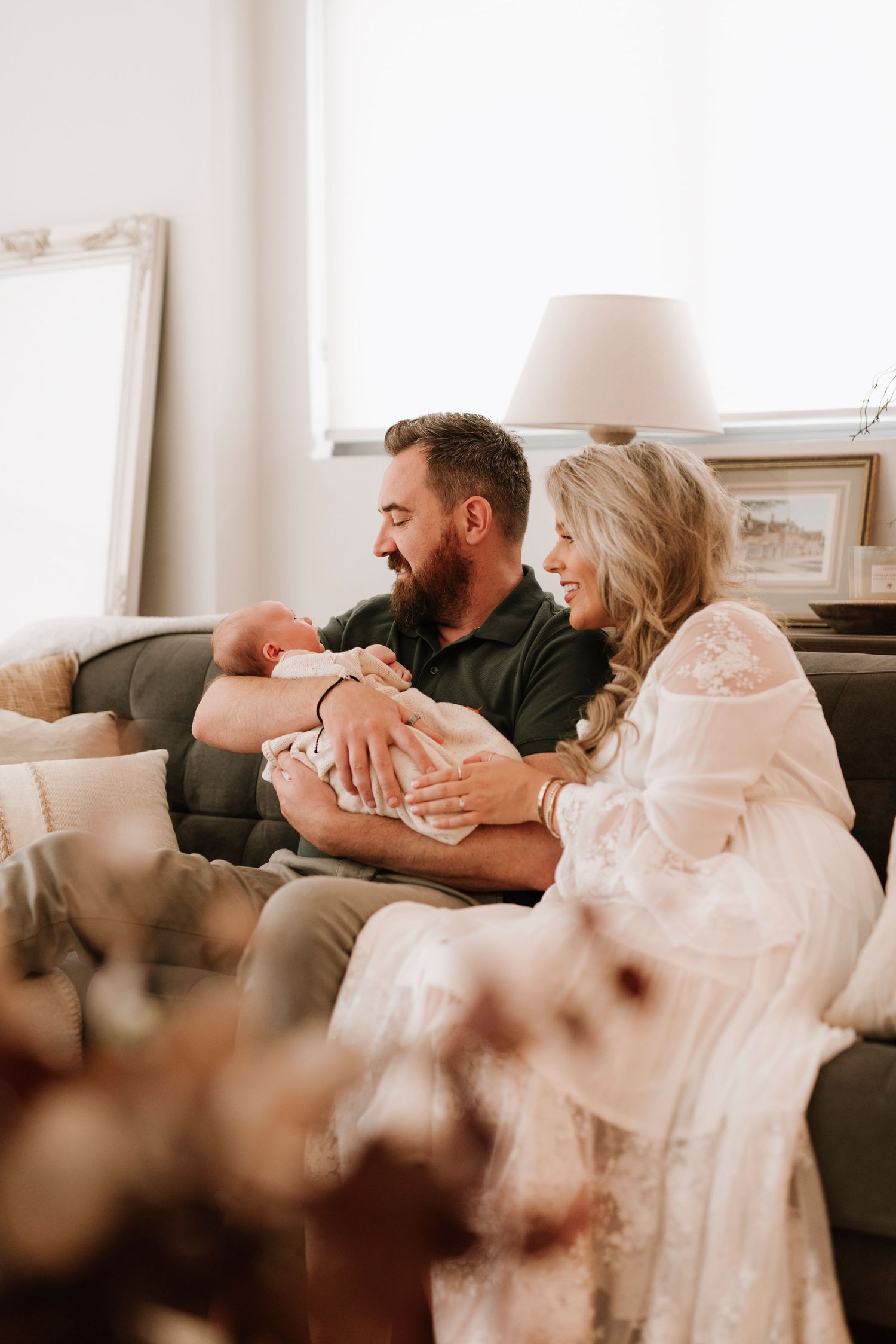 Turramurra newborn photography of parents holding baby together on couch in relaxed in-home setting
