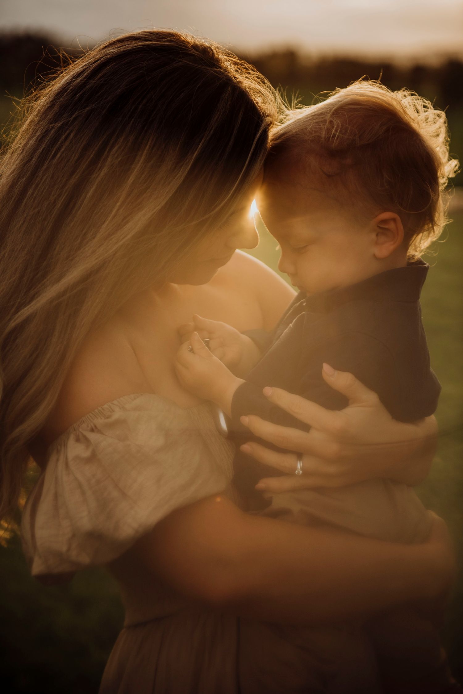 Northern Beaches family photography of mother holding baby close in warm golden sunset light