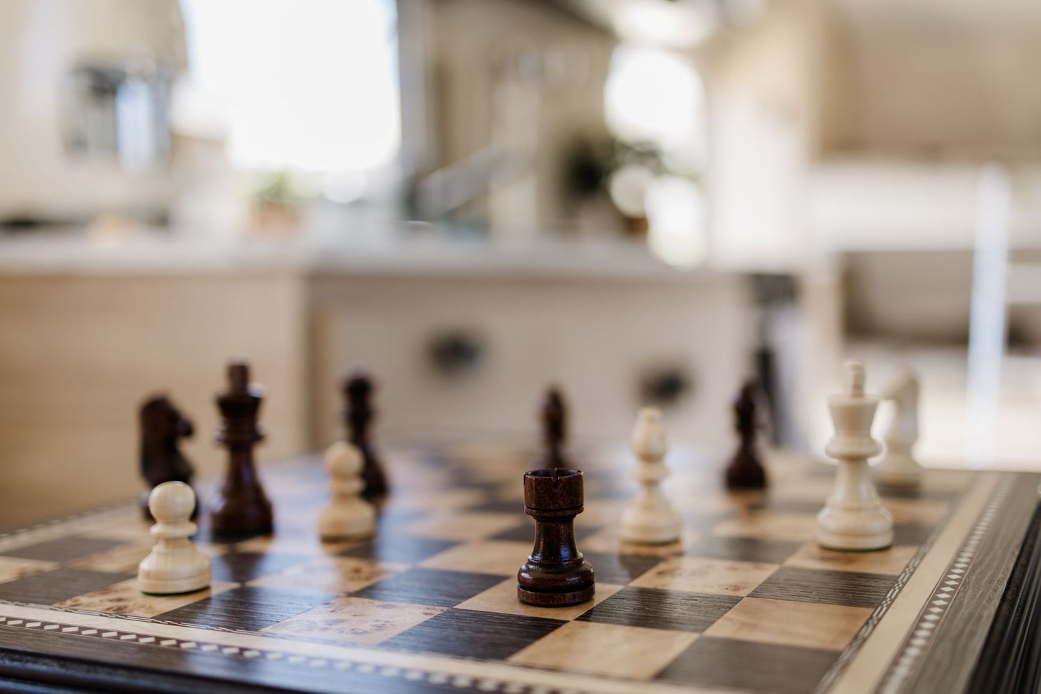 A close-up view of black and white chess pieces on a chessboard showing multiple pieces in selective focus.