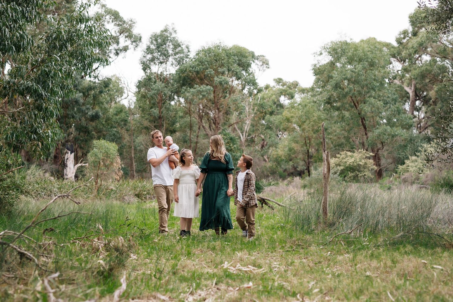 Family enjoying a picnic together in a wooded eucalyptus grove on a sunny day.