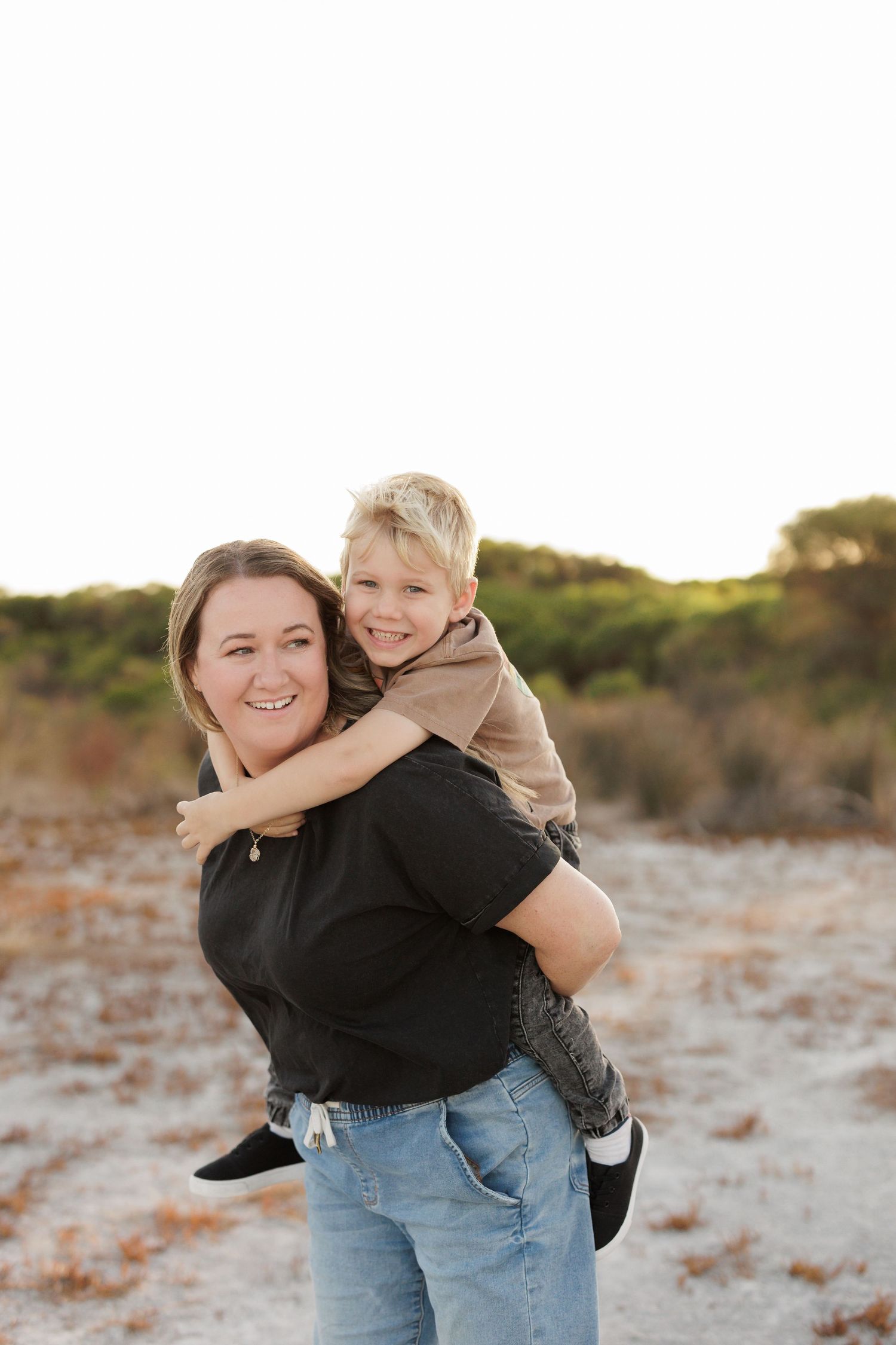 A piggyback ride shared on a sandy beach during golden hour.