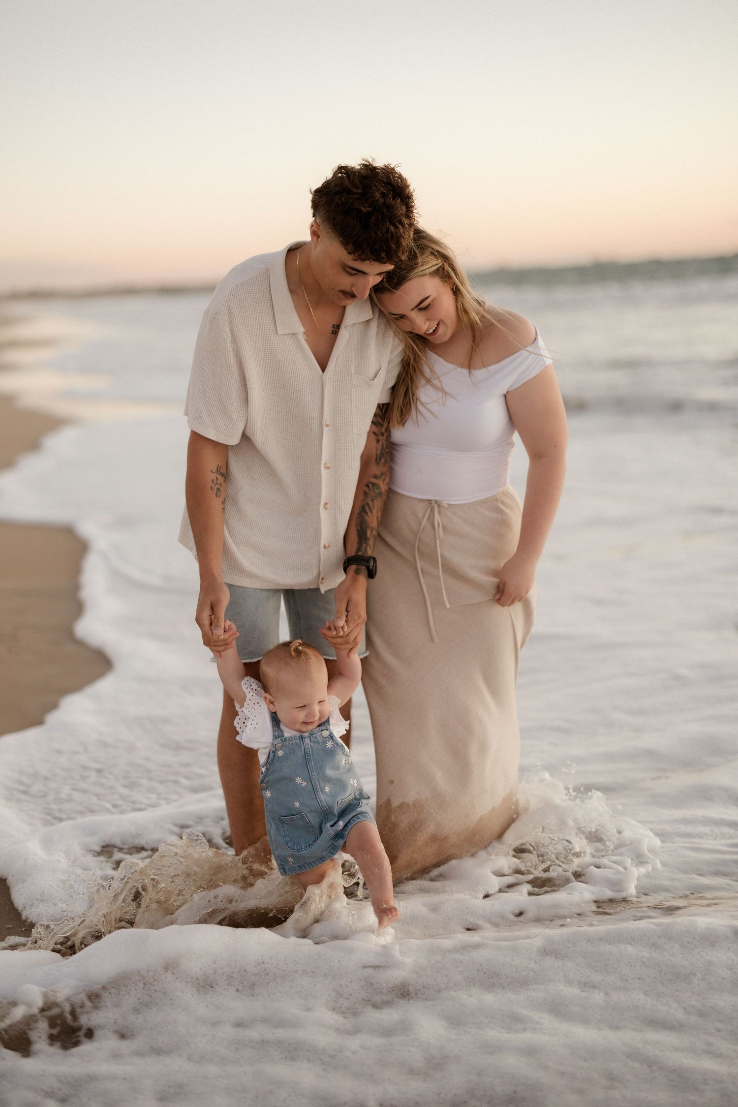 Family enjoying playful moments in the ocean waves at sunset.