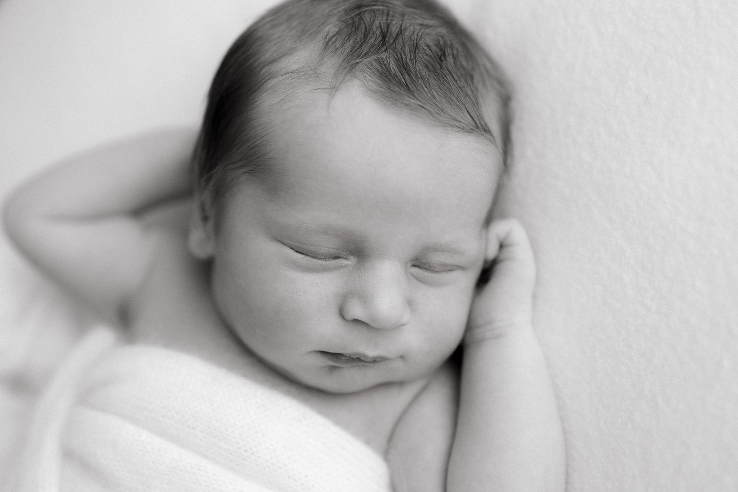 Black and white portrait of sleeping newborn with peaceful expression.