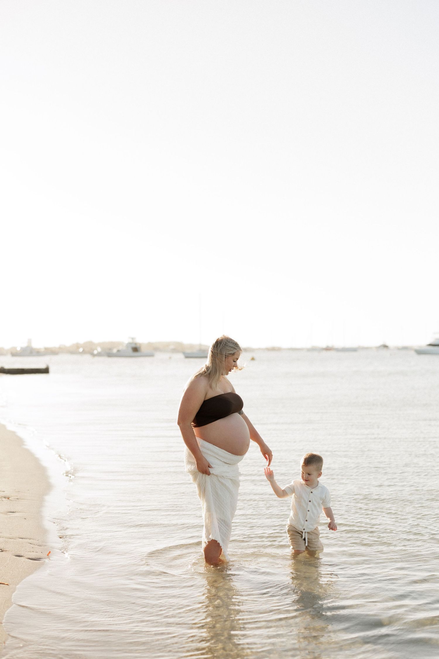 Family enjoying a playful moment together in shallow ocean waters at sunset.