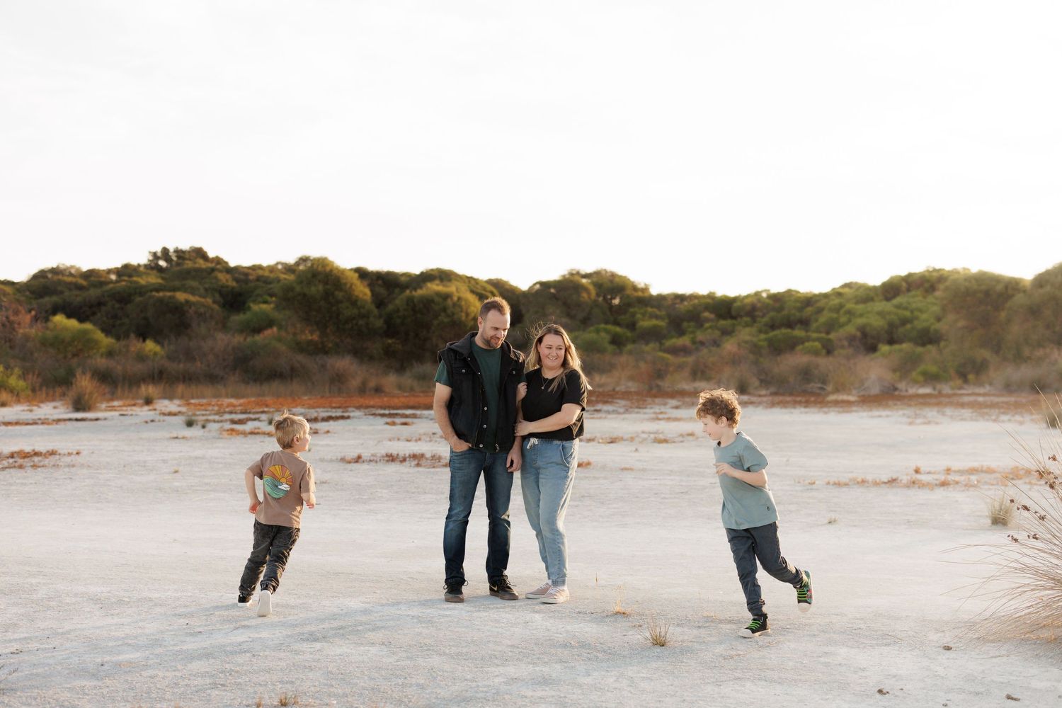 A family enjoying a playful moment together on a sandy beach at sunset.