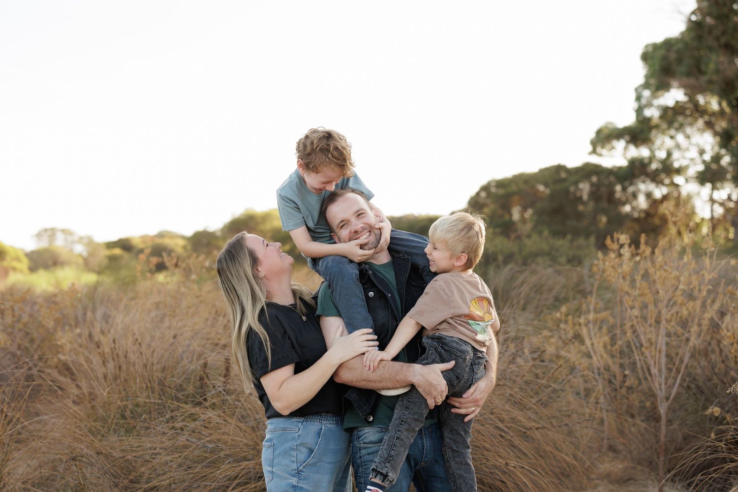 Family group sharing loving embrace outdoors during sunset.