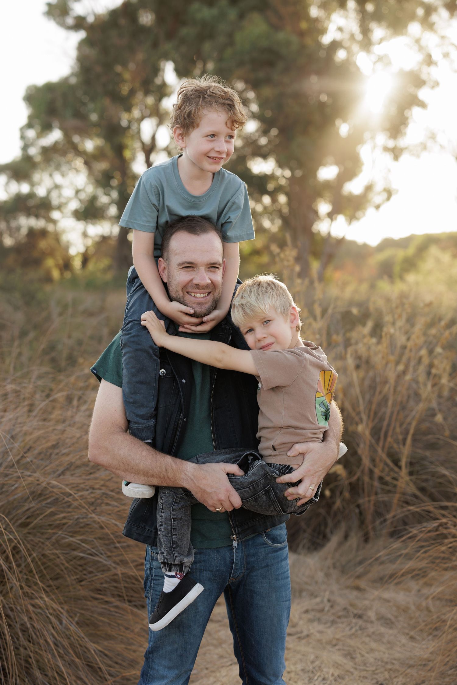 Three people sharing a playful moment outdoors during golden hour.