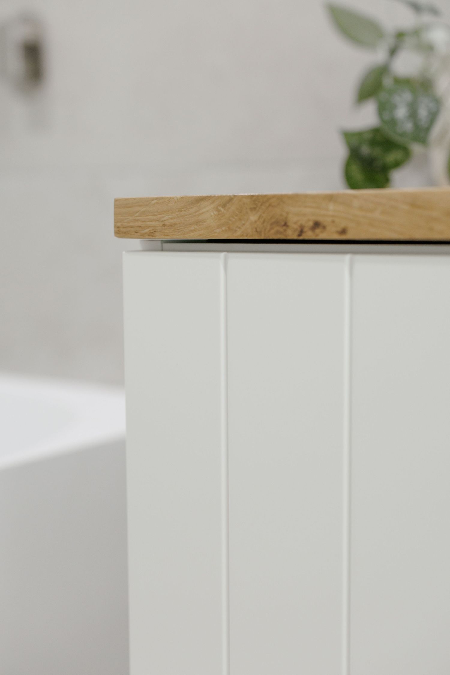 Close-up view of a wooden shelf or tabletop edge meeting white painted wall, showing minimal modern interior design detail.