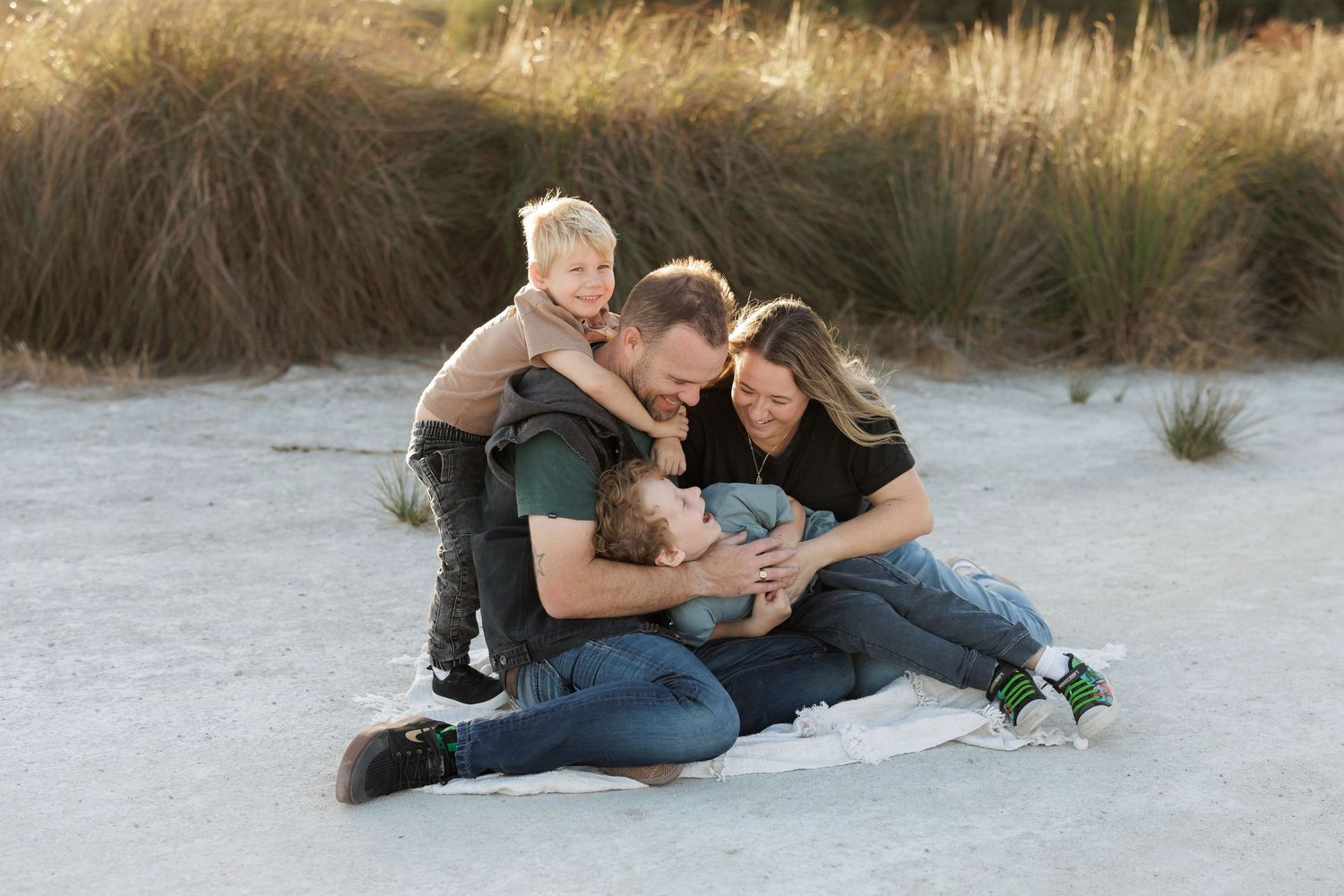 A family shares an intimate moment together while sitting on a blanket outdoors.