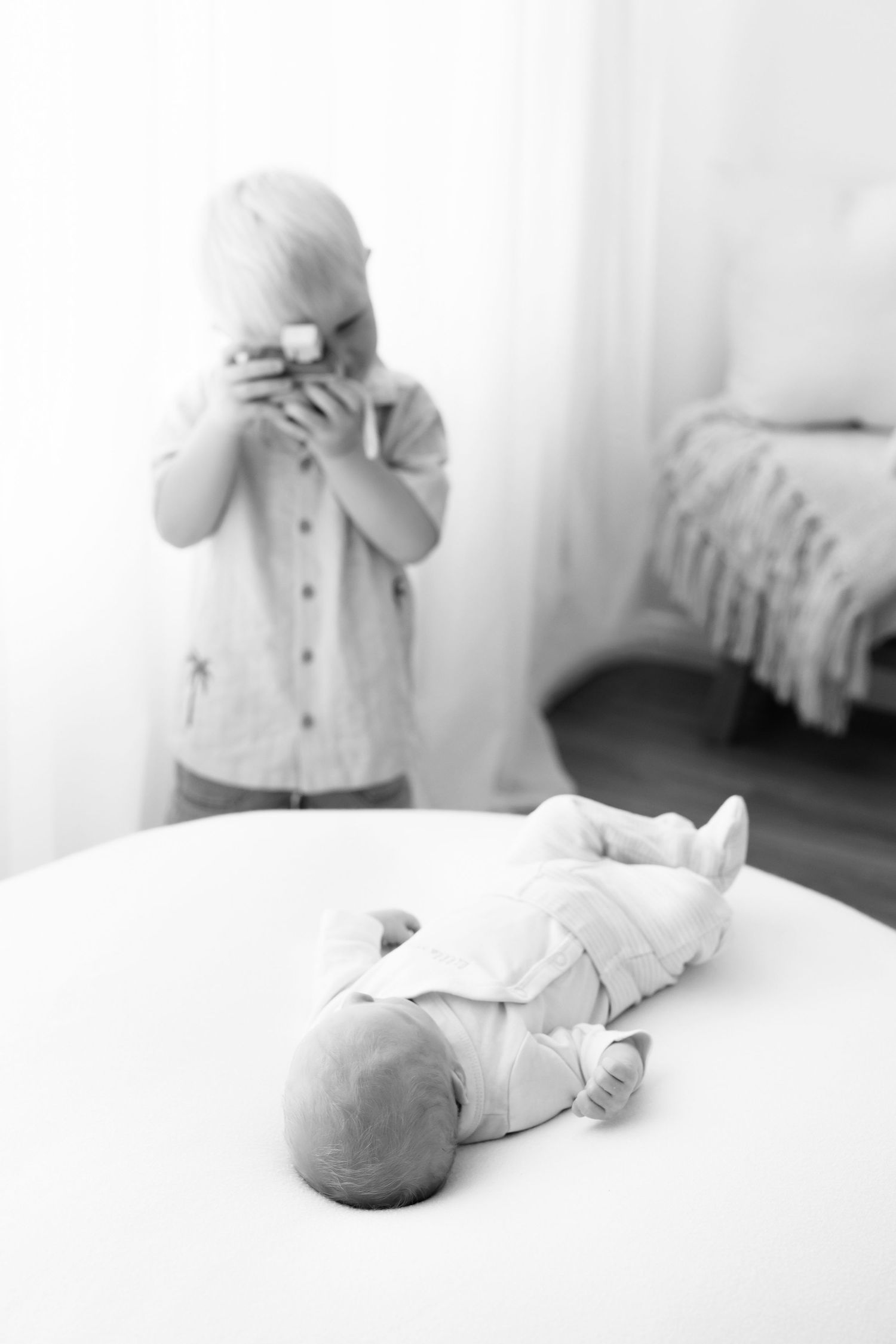Artistic black and white sequence showing a baby lying on white bedding.