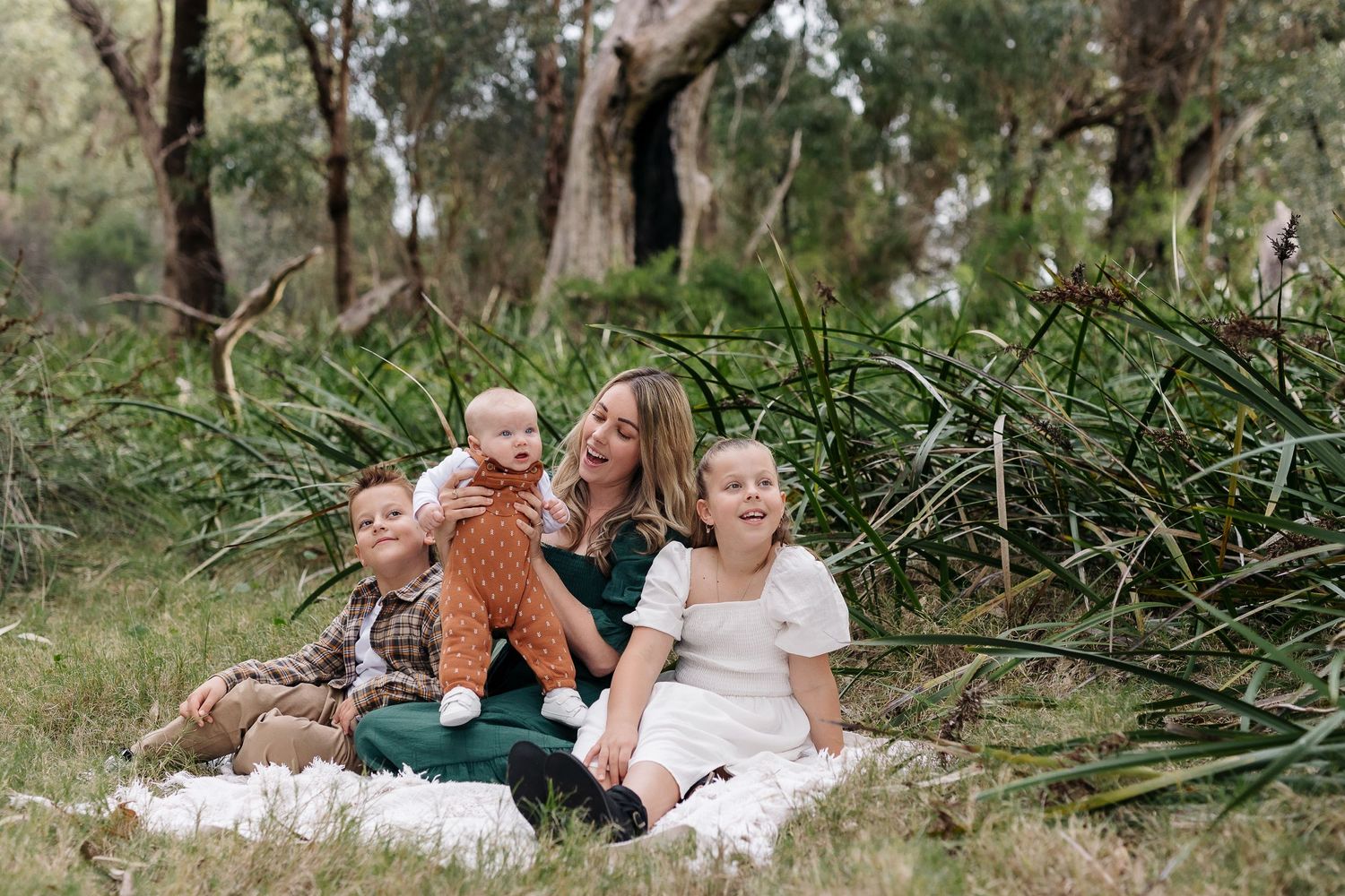 A family sharing a tender moment together outdoors among fallen branches and natural surroundings.