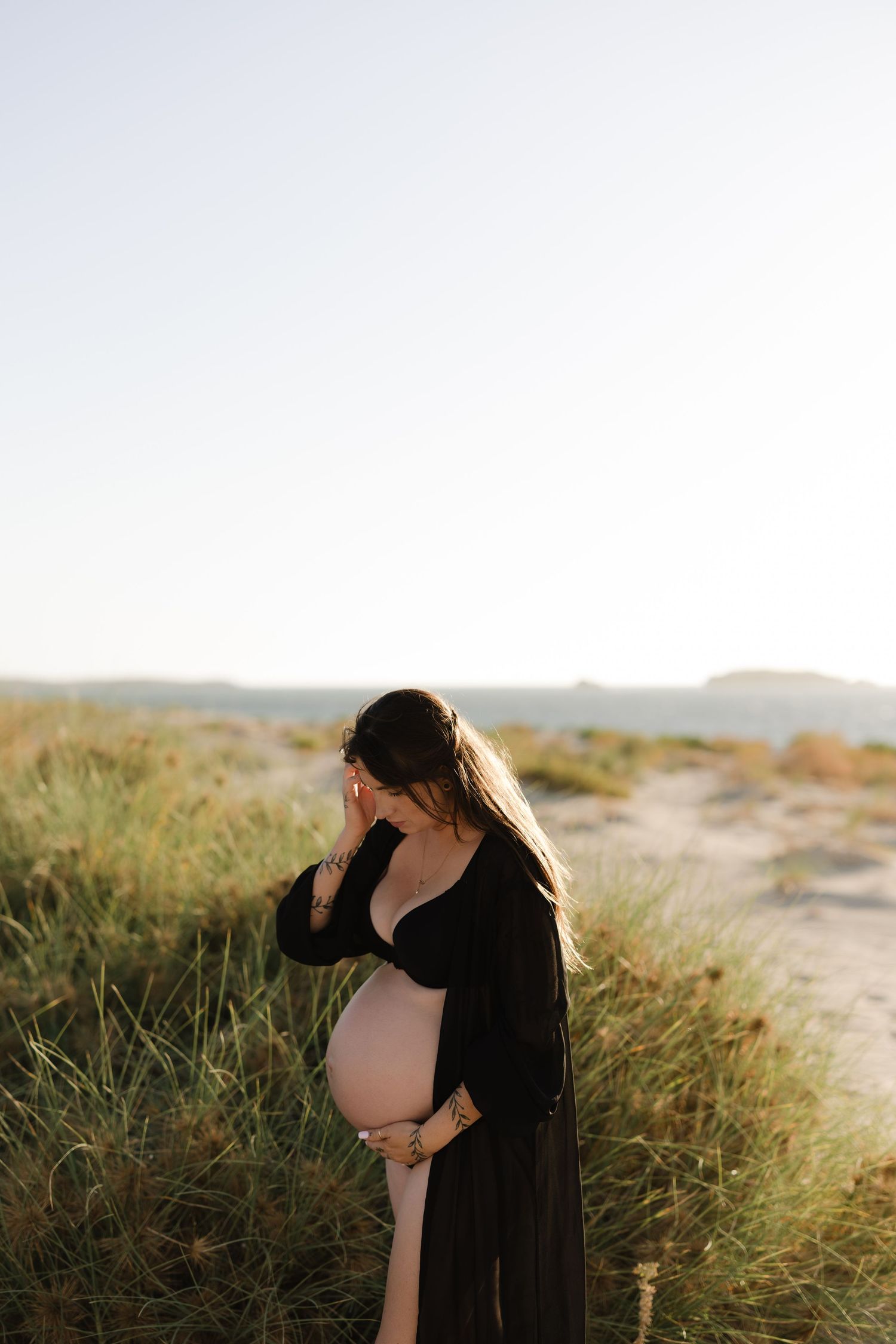 Maternity silhouette portrait against sunset in natural outdoor setting.